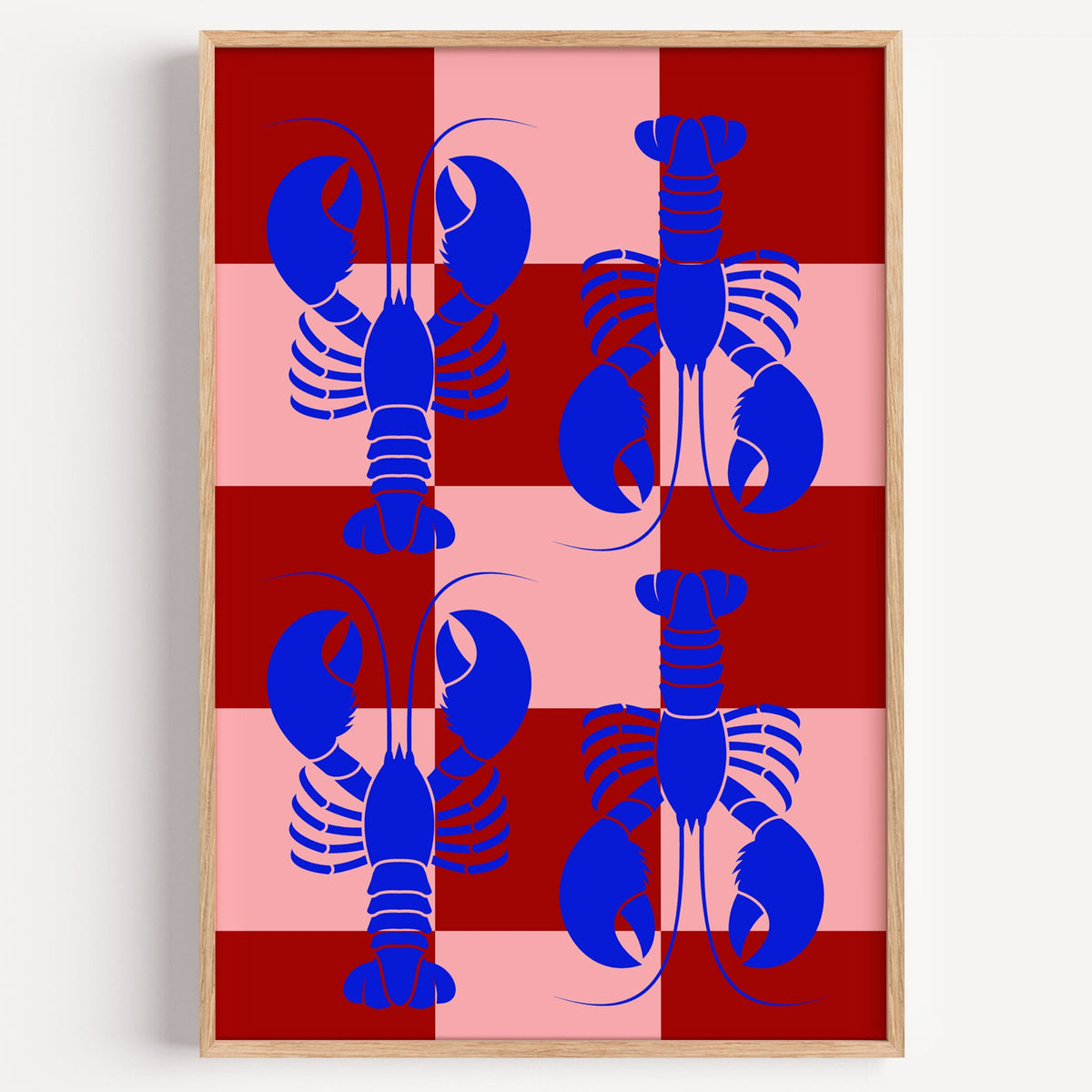 Blue lobster red pink checker print in a light oak frame on a plain white wall