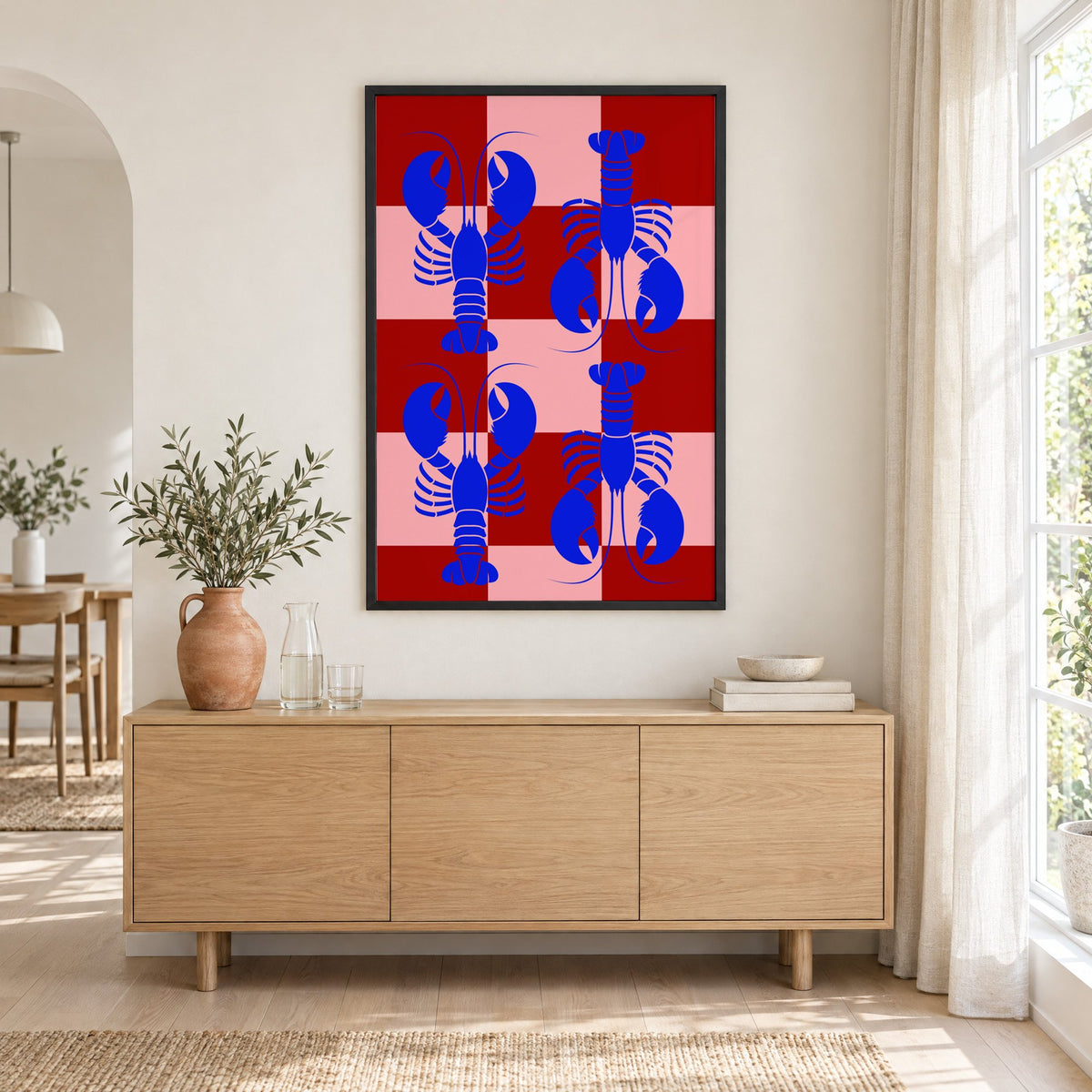 Blue lobster red pink checker print in a black frame above an oak sideboard with a terracotta vase of olive branches