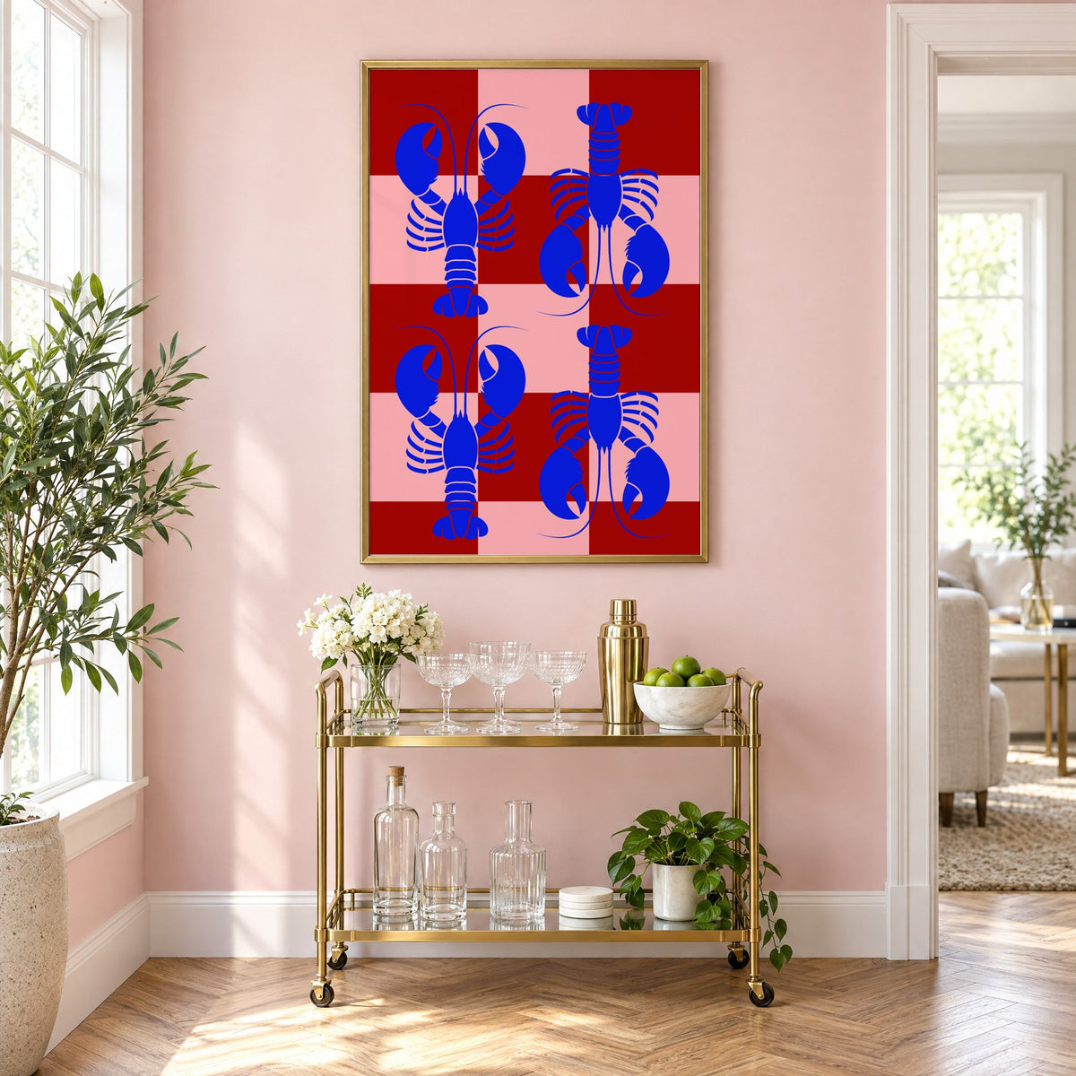Blue lobster red pink checker print in a brass frame above a gold bar cart on a blush pink wall