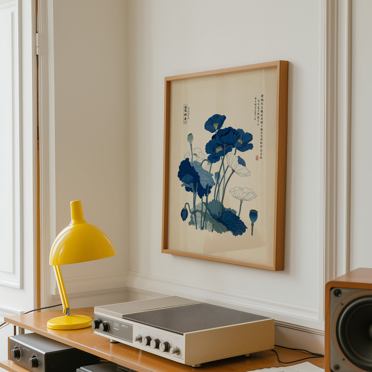 Blue and white poppies poster in an oak frame above a vintage hi-fi shelf with a yellow desk lamp