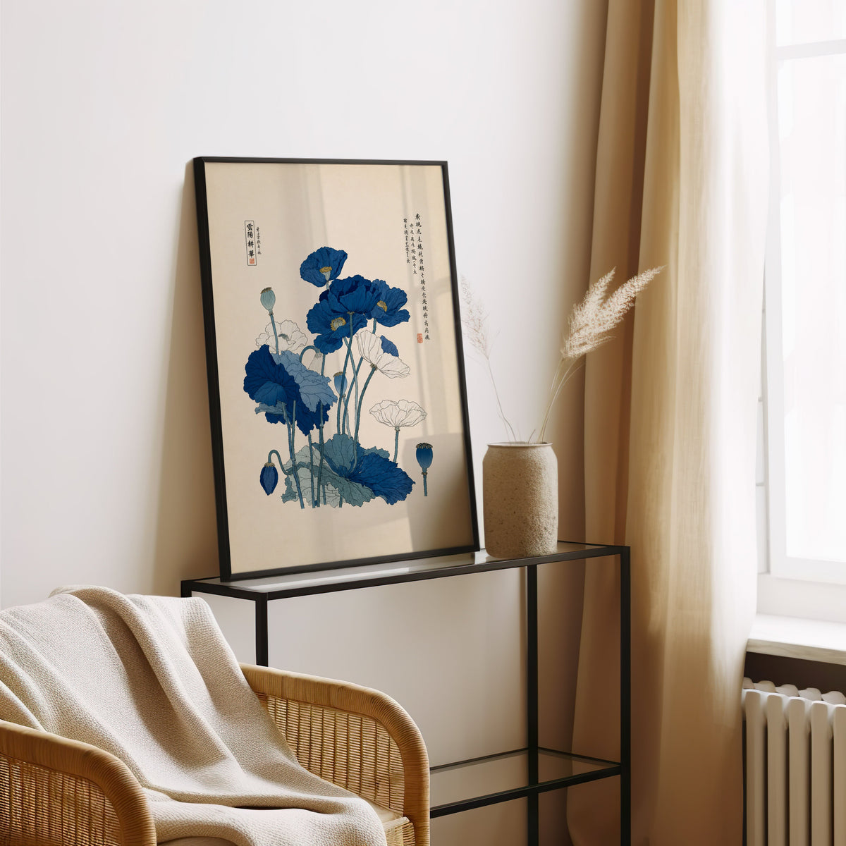 Blue and white poppies poster in a black frame leaning on a glass console beside pampas grass