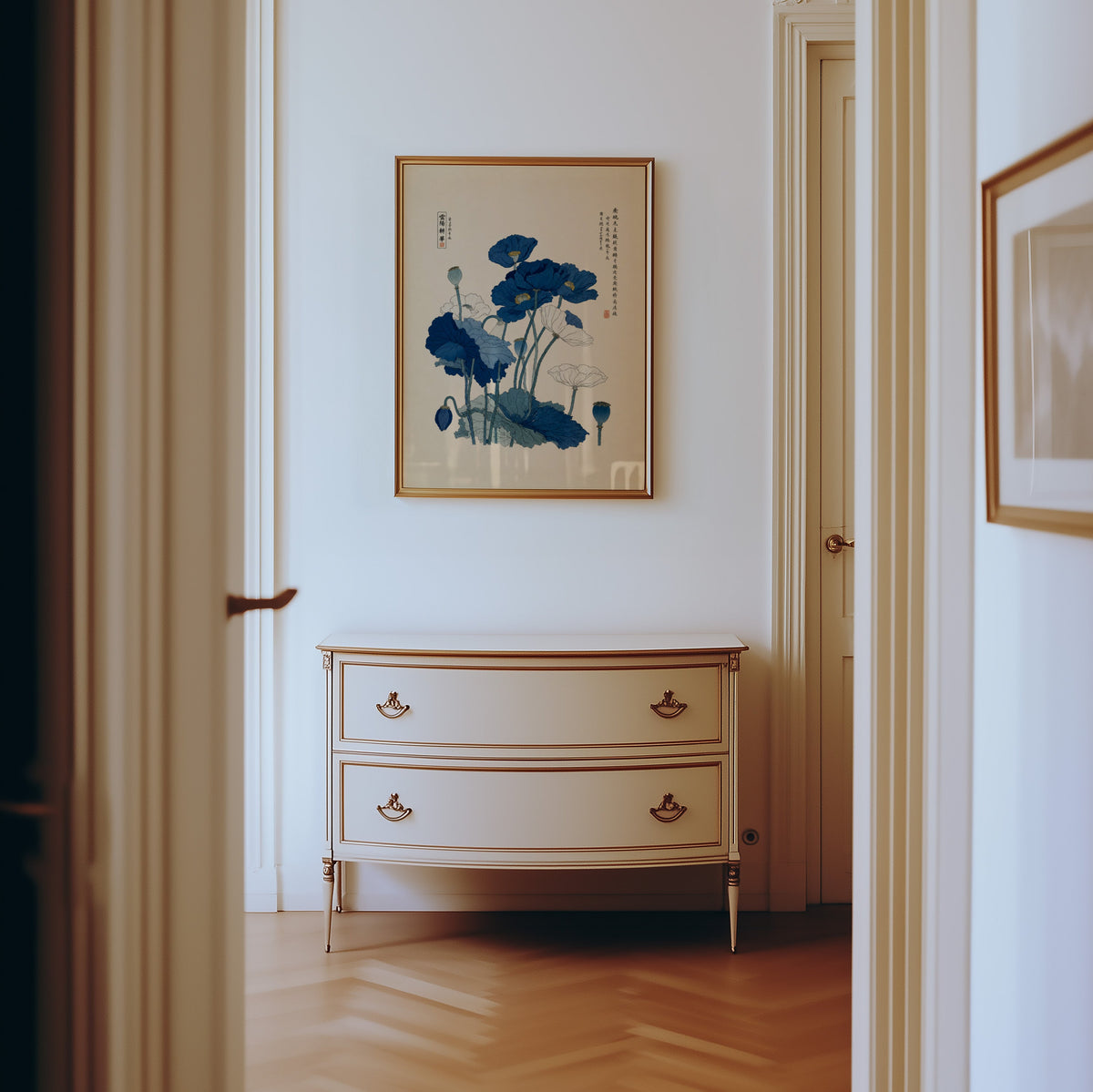 Blue and white poppies poster shown in a gold frame in a hallway above a cream dresser