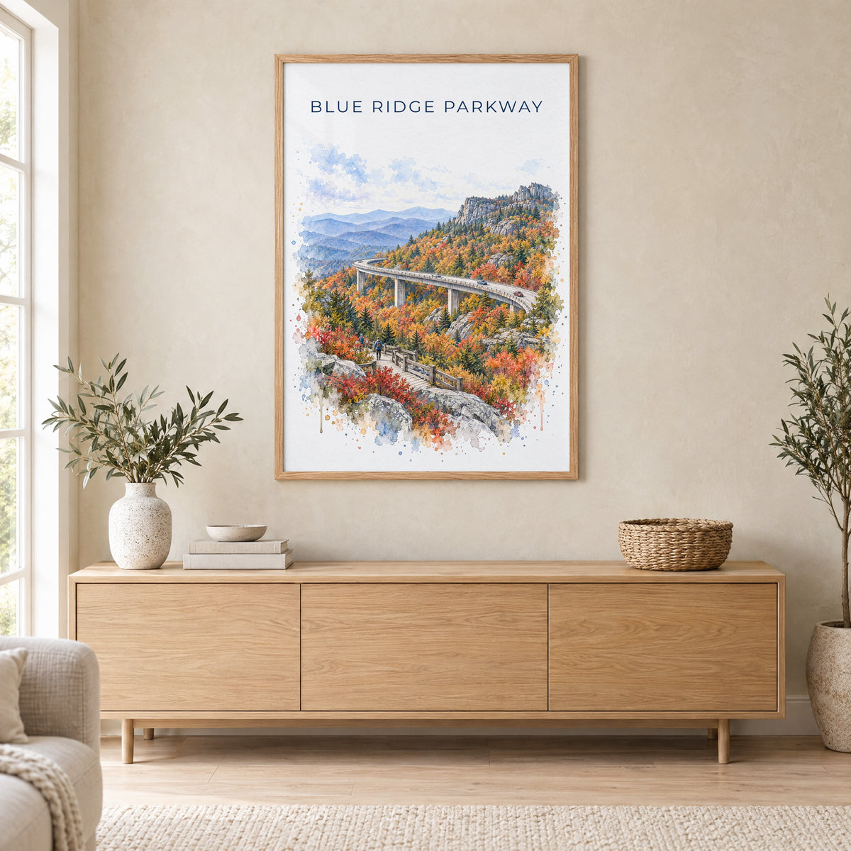 Blue Ridge Parkway watercolor print in an oak frame above a light wood sideboard in a Scandinavian living room