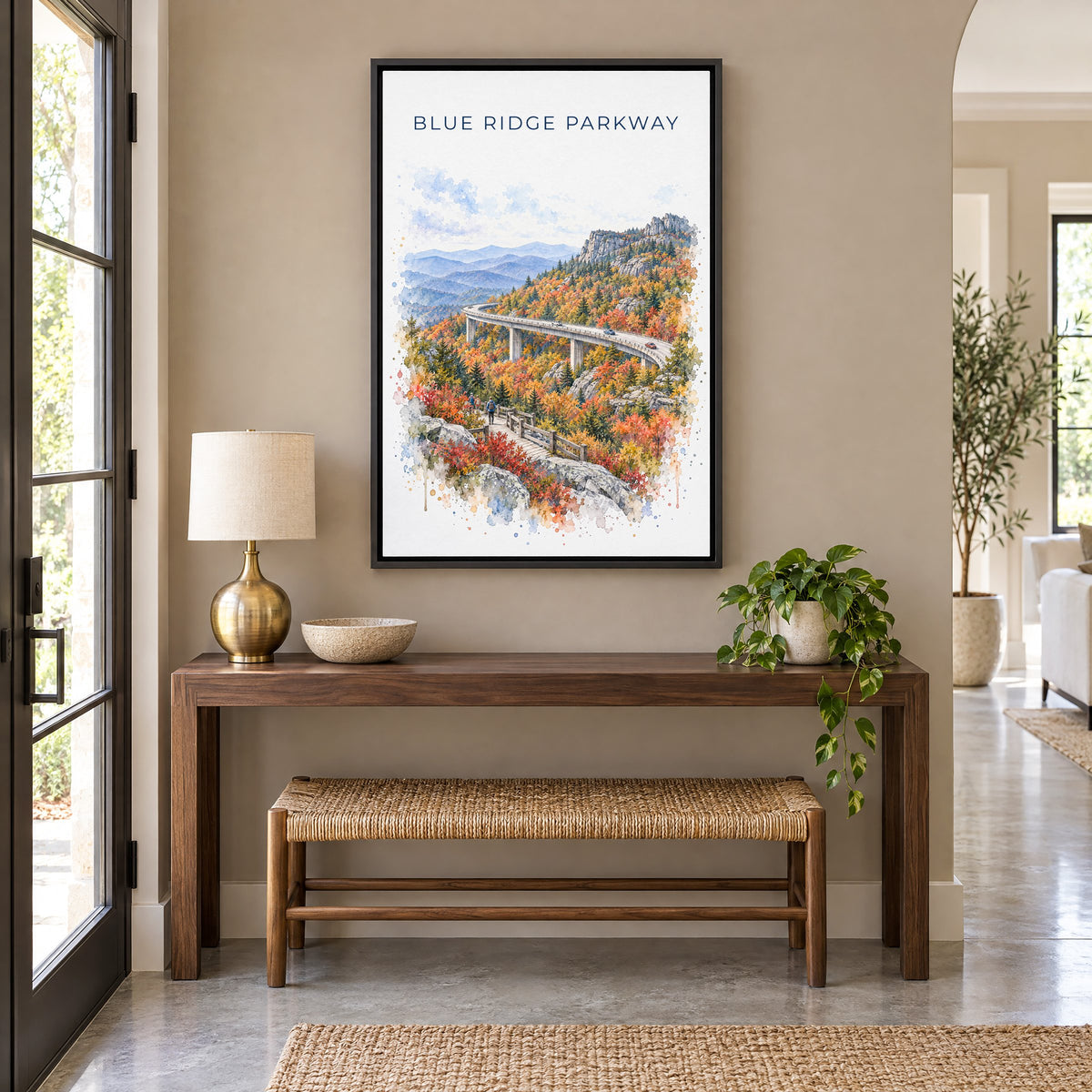 Blue Ridge Parkway watercolor print as a black floater canvas above a walnut console and woven bench in an entryway