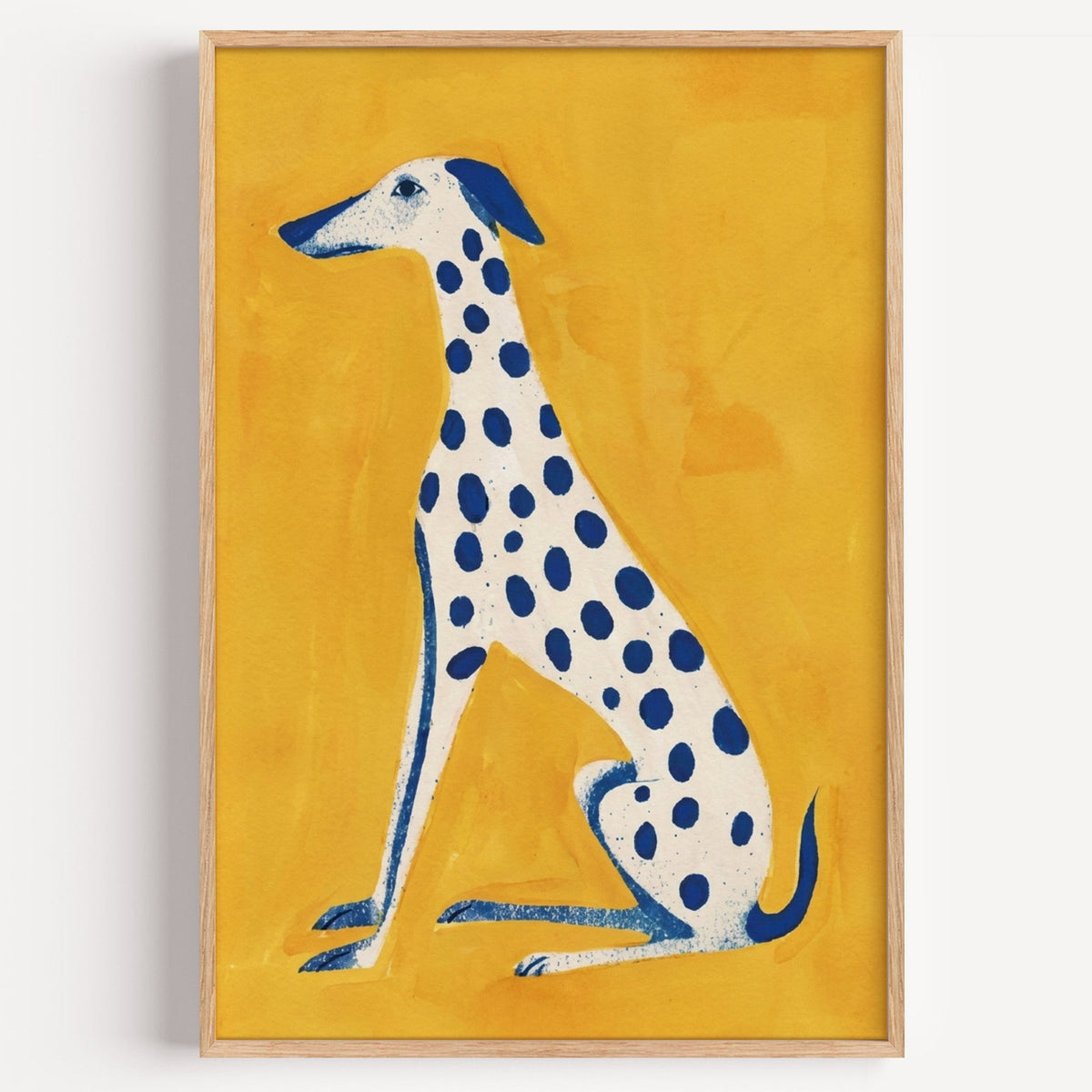 Blue spotted dog print in a light oak frame on a plain white wall