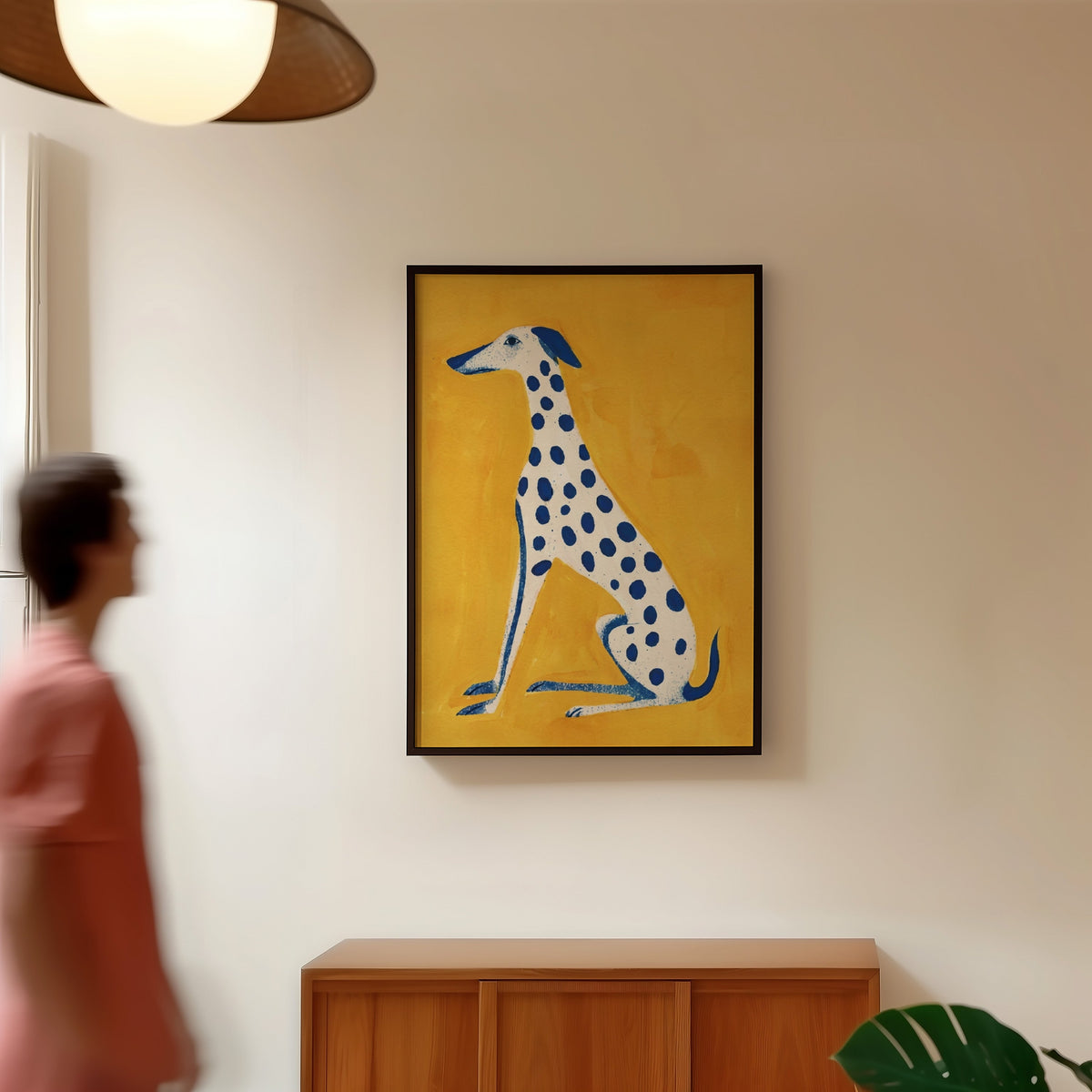 Seated hound portrait print in a black frame in a hallway under a rattan pendant