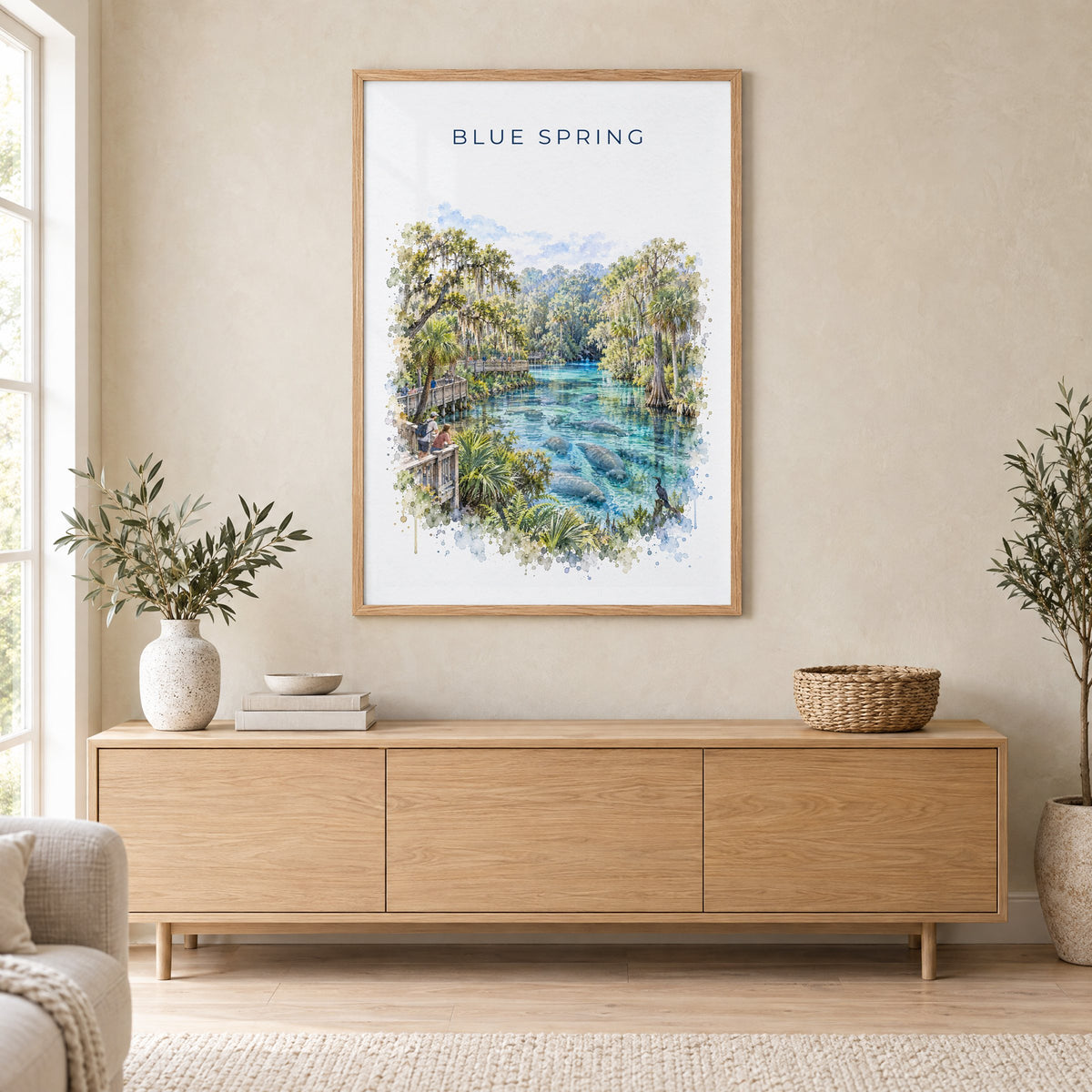 Blue Spring State Park watercolor print in an oak frame above a light wood sideboard in a Scandinavian living room
