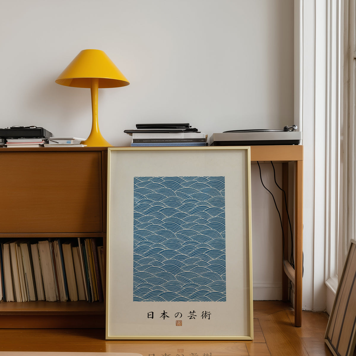 Blue wave line pattern poster shown in a gold frame leaning under a teak desk with a yellow lamp