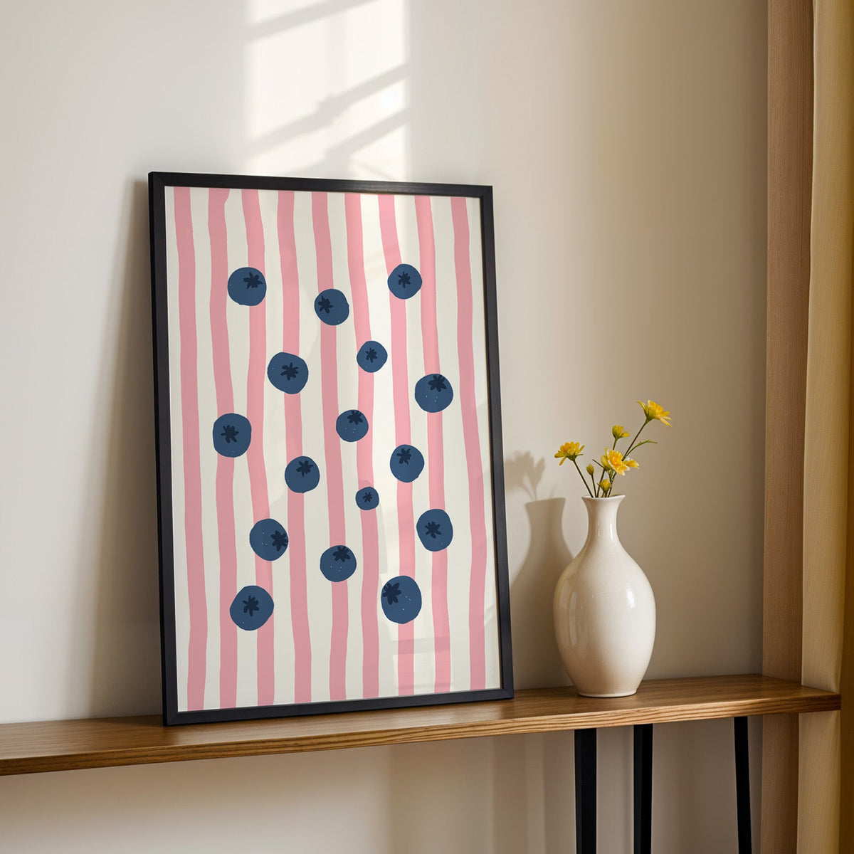 Blueberry stripe print in a black frame on a console table with yellow daisies
