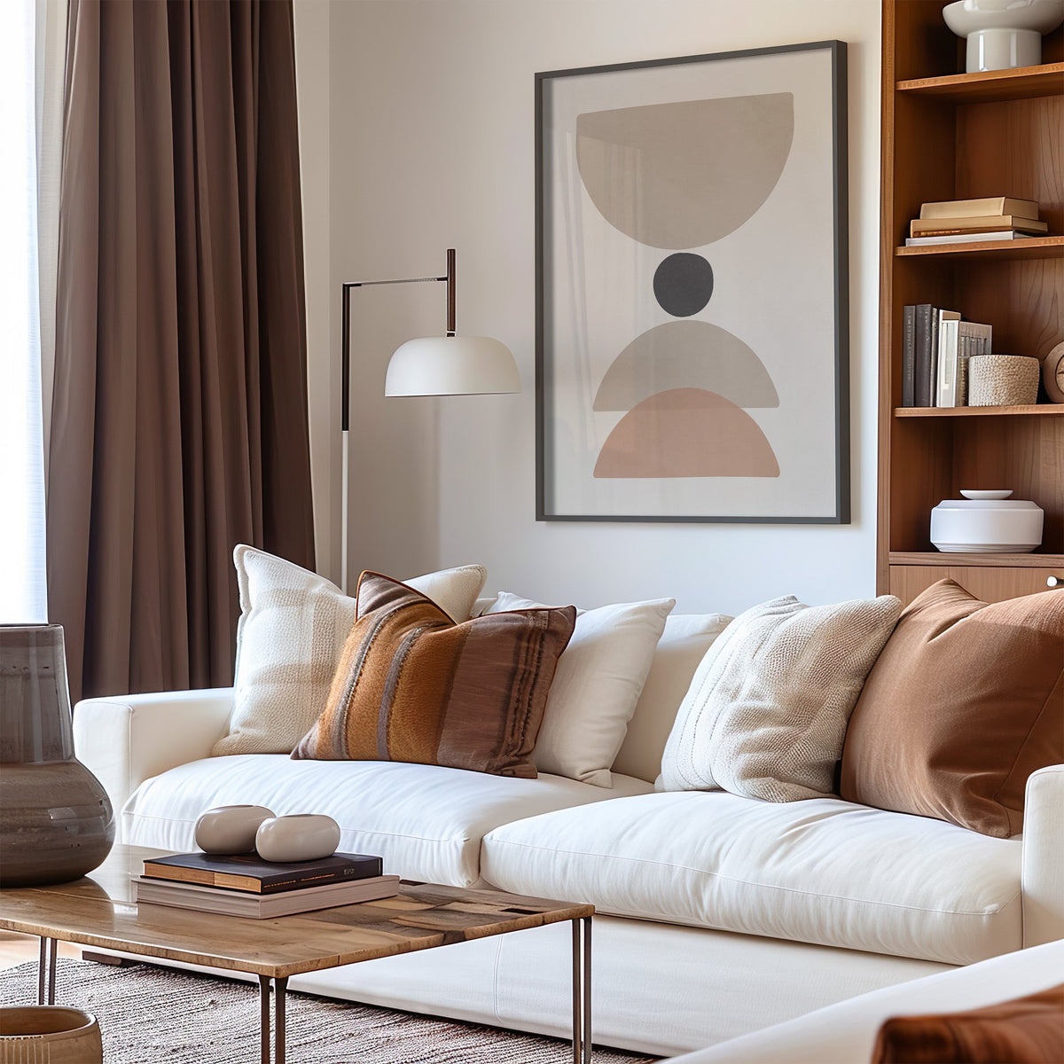 Taupe bowl, charcoal dot and blush arch print in a black frame above a cream sofa with brown striped pillows