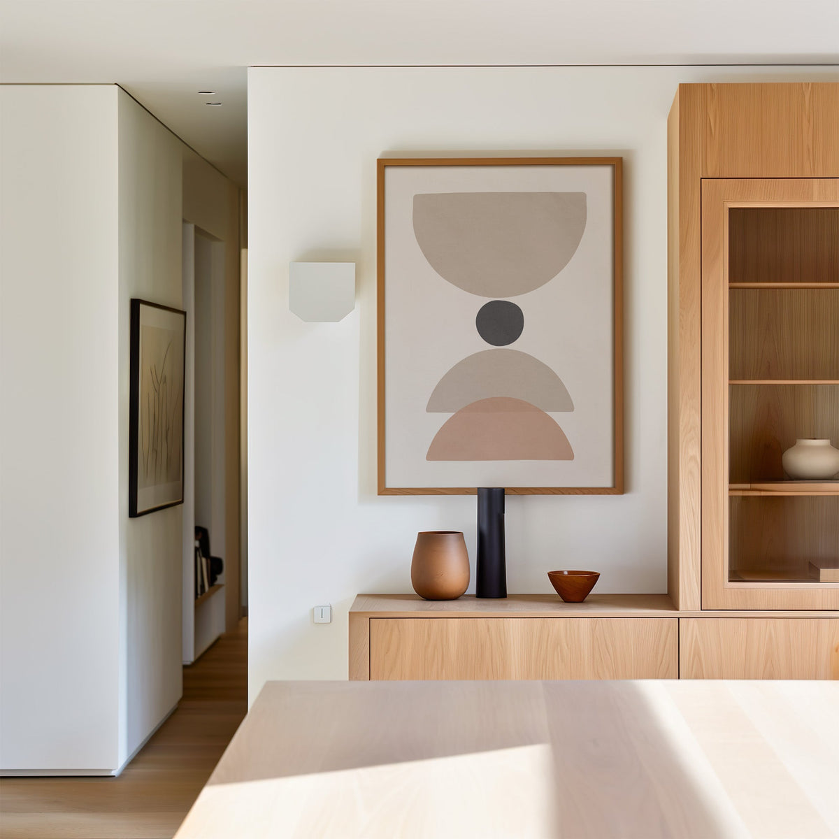 Taupe bowl, charcoal dot and blush arch print in an oak frame above a light oak sideboard in a dining room