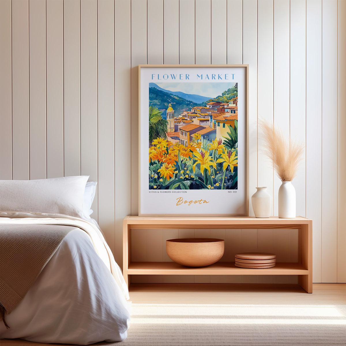 Bogota flower market print in an oak frame on a wood bench against a white shiplap bedroom wall with pampas grass