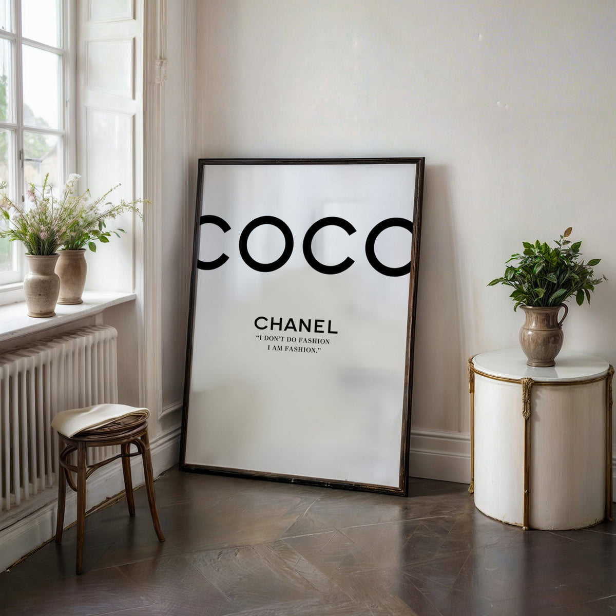 Giant cropped black letters with fashion quote print in a black frame on a dark stone floor beside a white side table