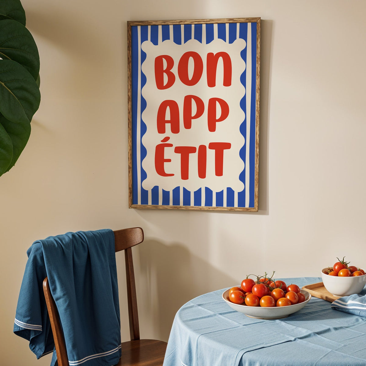 Bon appetit print in an oak frame above a blue linen table with ripe tomatoes