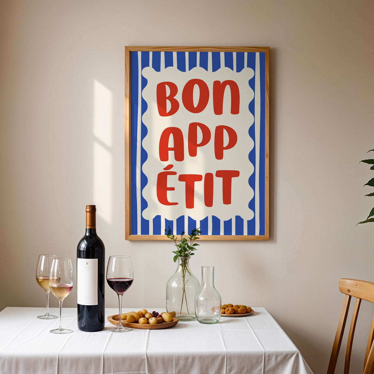 Bon appetit print in an oak frame above a table laid with red wine and glasses