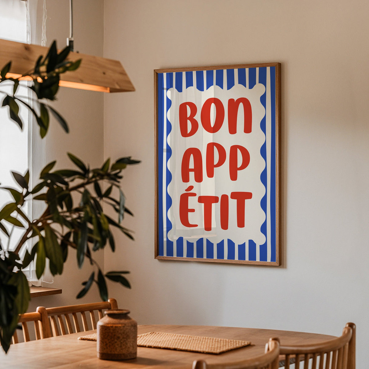 Bon appetit print in a walnut frame above a dining table beside an olive tree