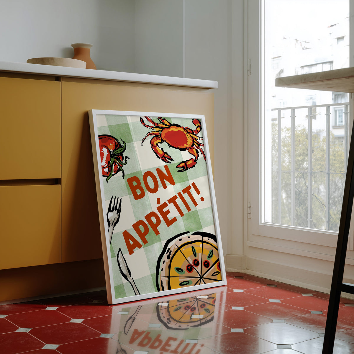 Bon Appetit crab print in a white frame against yellow cabinets on a red tiled floor