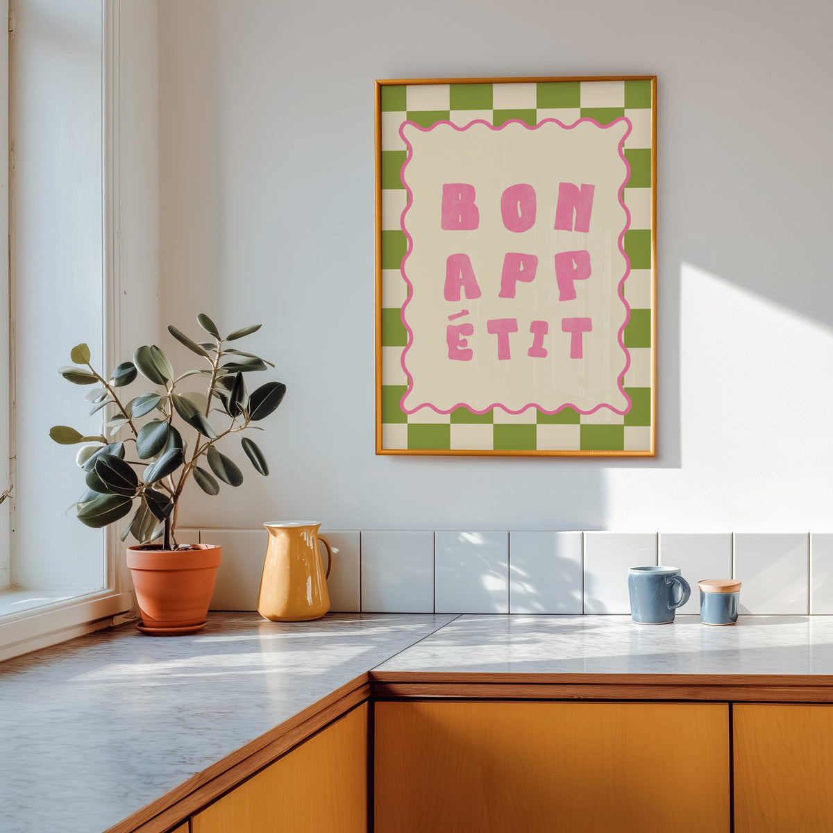 Bon Appetit check print shown in a gold frame above a marble counter with a yellow ceramic jug