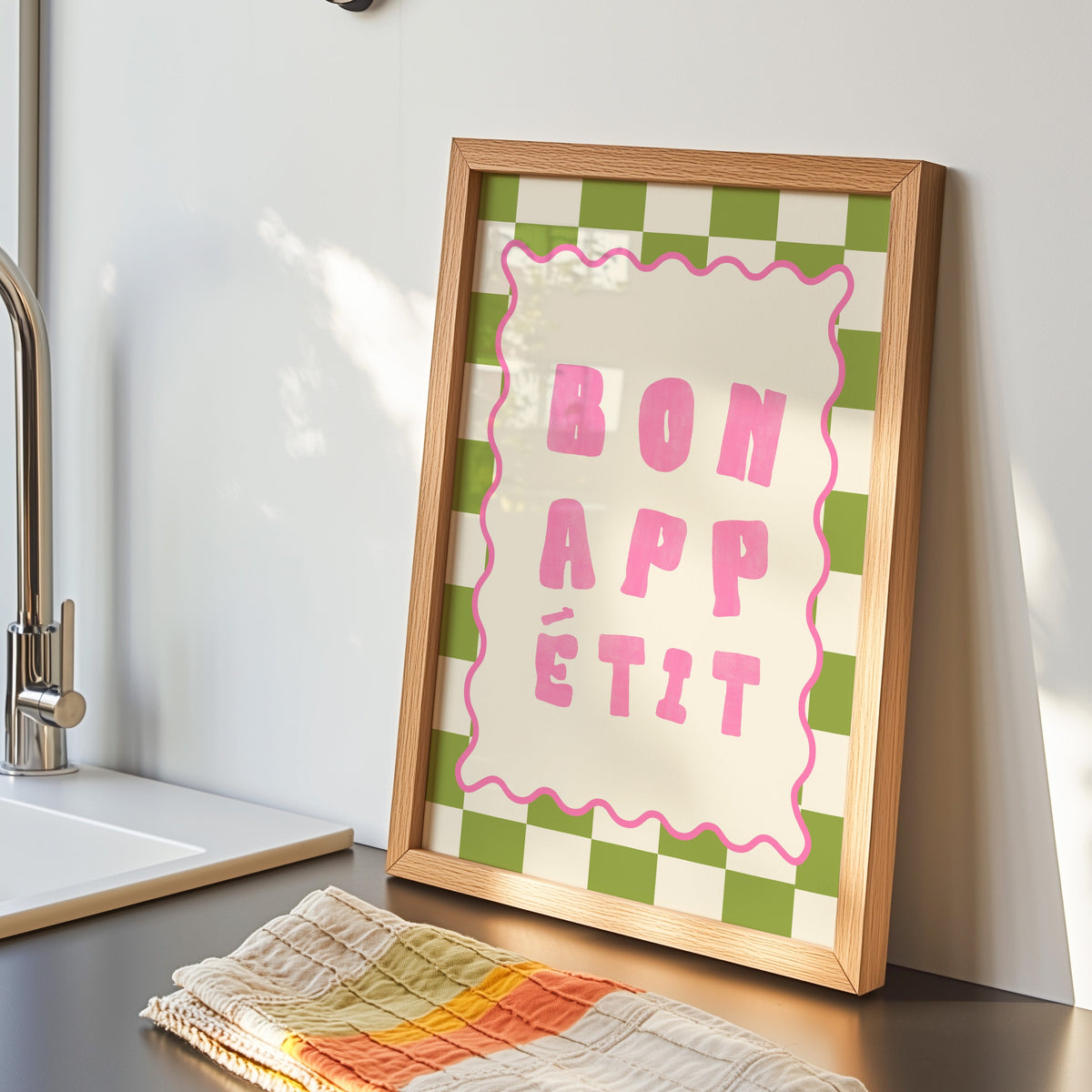 Bon Appetit check print in an oak frame by the kitchen sink beside a striped tea towel