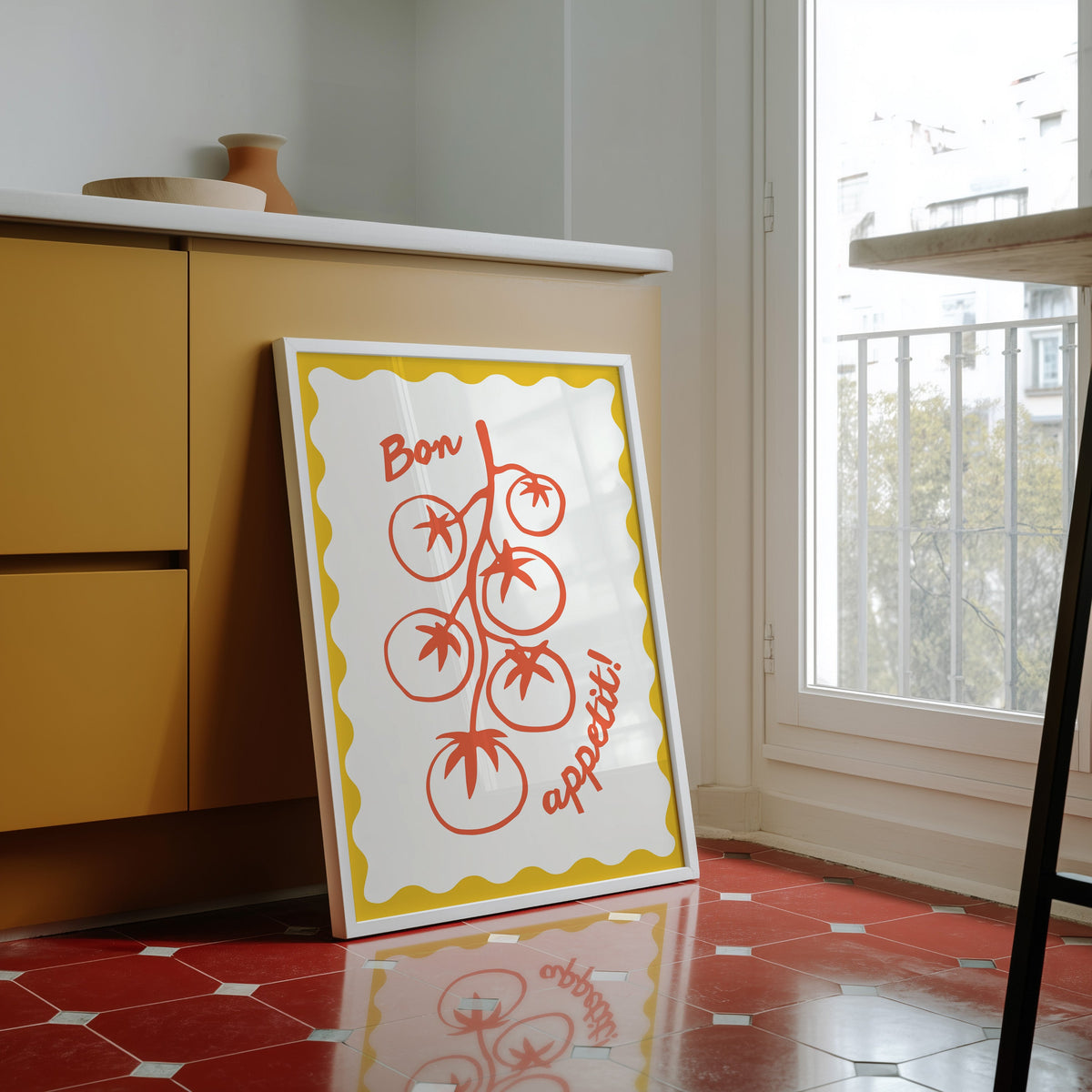 Tomato vine print in a white frame against yellow cabinets on a red tiled floor