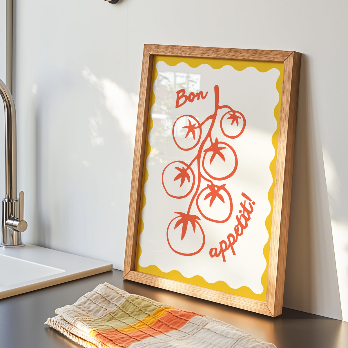 Tomato vine print in an oak frame by the kitchen sink beside a striped tea towel