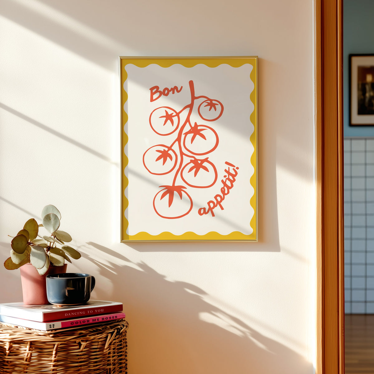 Tomato vine print shown in a gold frame above a basket of books and a pilea plant