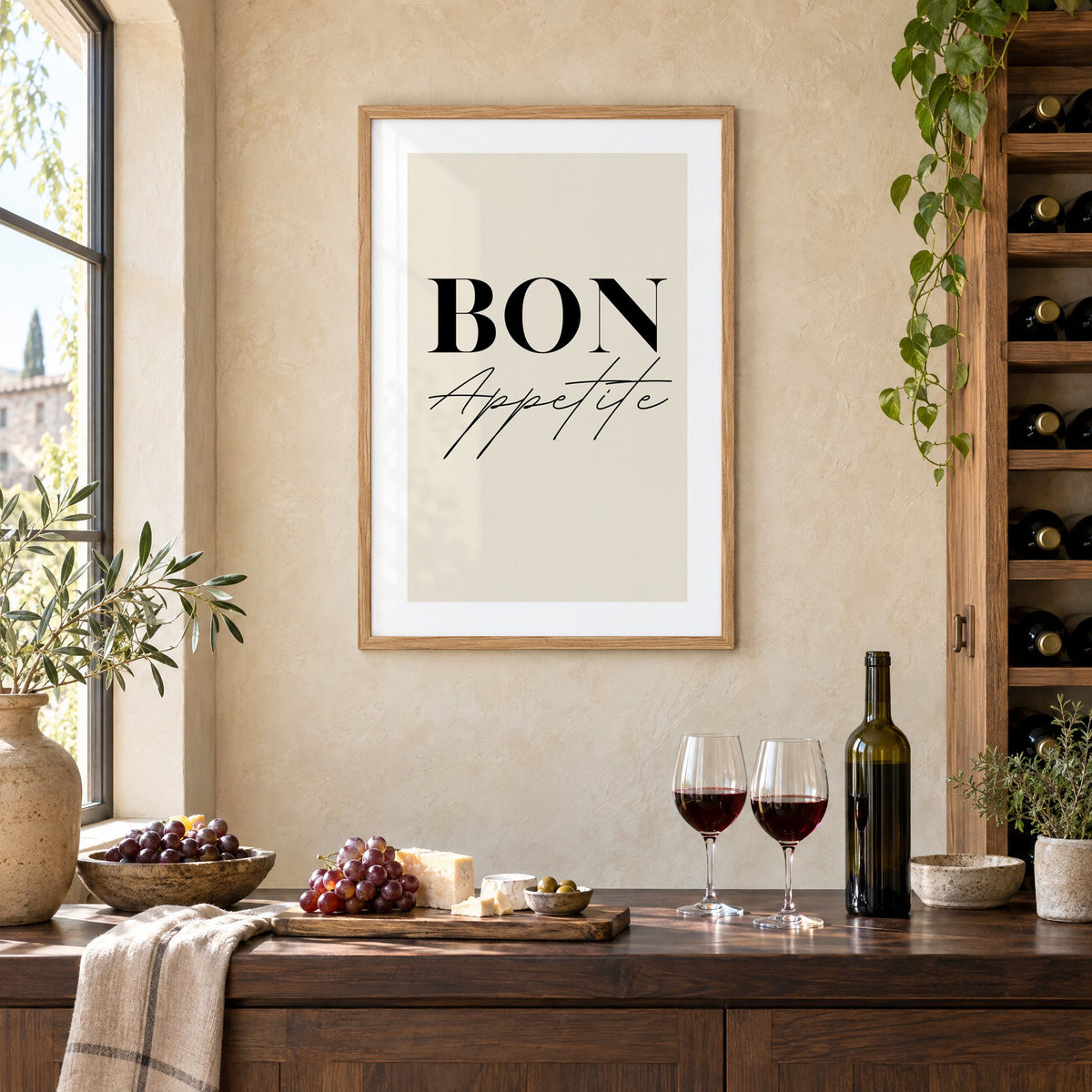 BON Appetite serif and script print in an oak frame on a limewashed wall above a wine counter with red wine, cheese and grapes