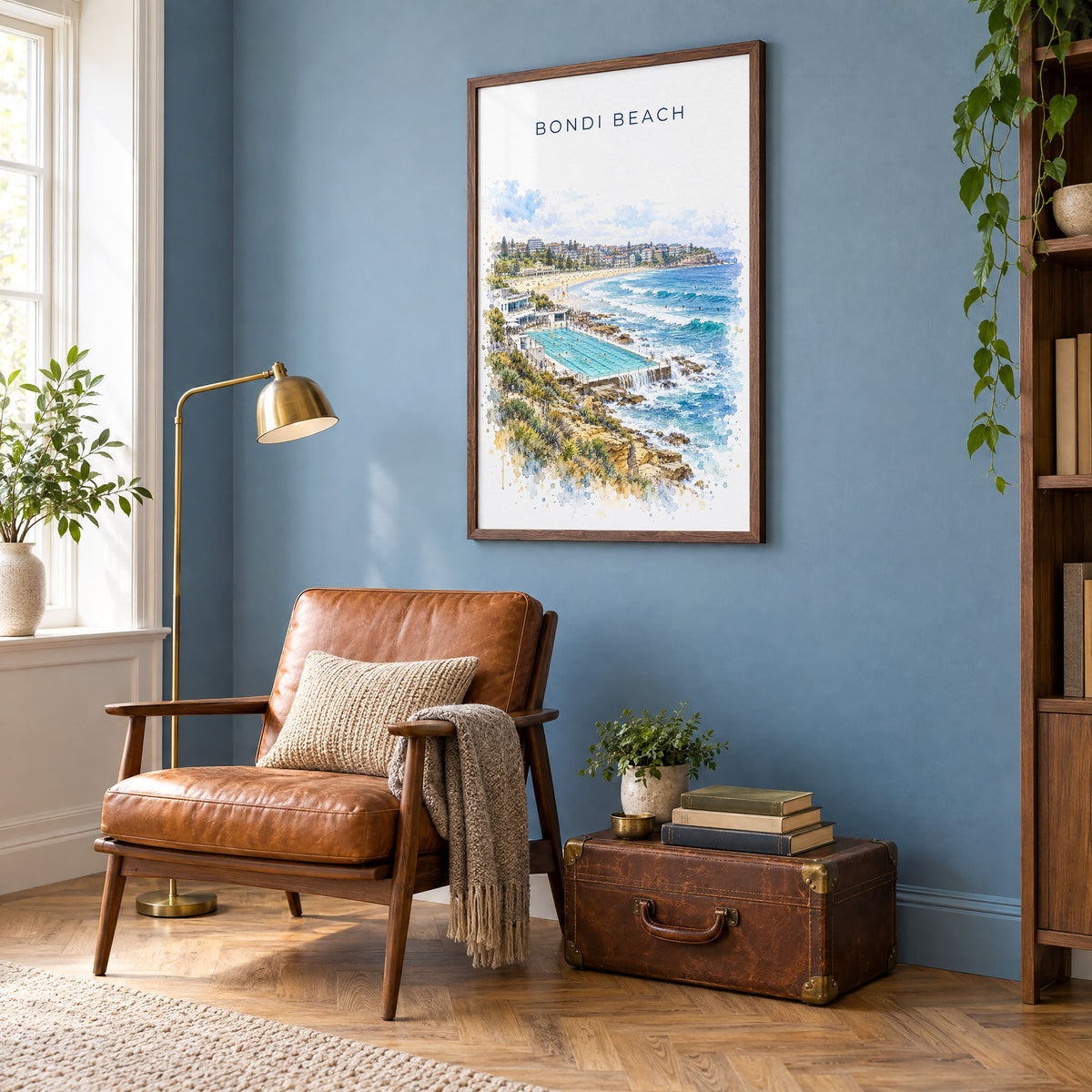Bondi Beach watercolor print in a walnut frame on a blue wall above a leather armchair in a reading nook