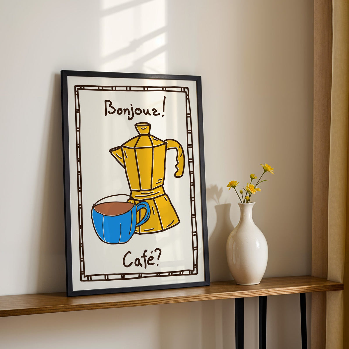 Bonjour cafe moka pot print in a black frame on a console table with yellow daisies