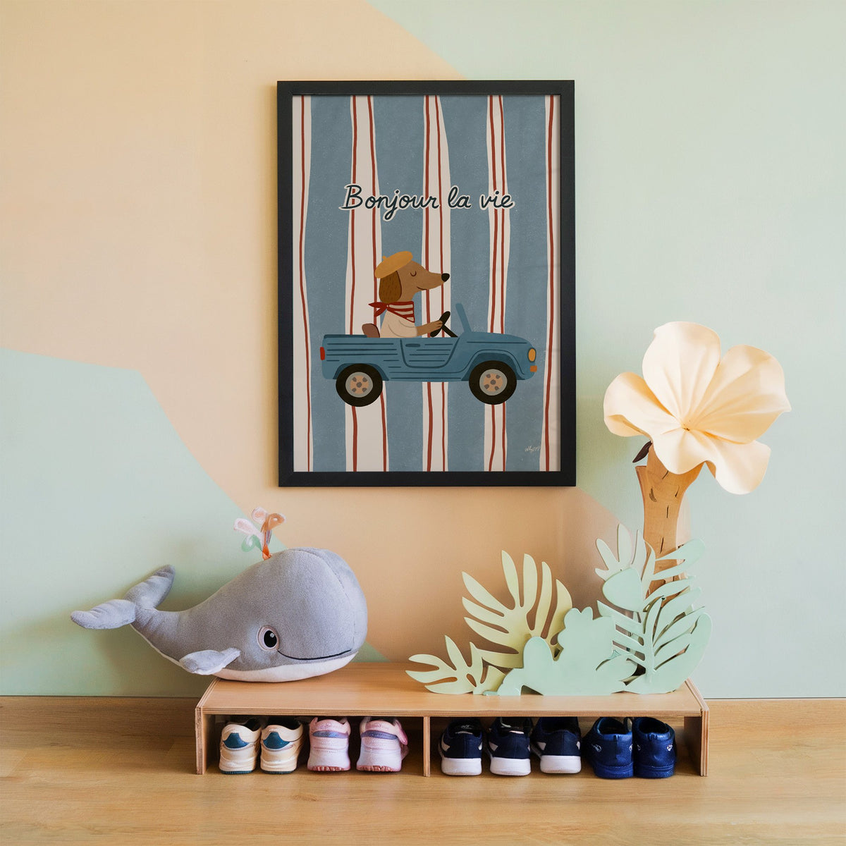 Dog driving car with french script nursery print in a black frame on a mint and peach wall above a whale plush