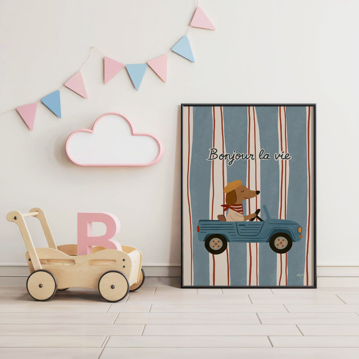 Dog driving car with french script nursery print in a black frame under pastel bunting by a wooden baby walker