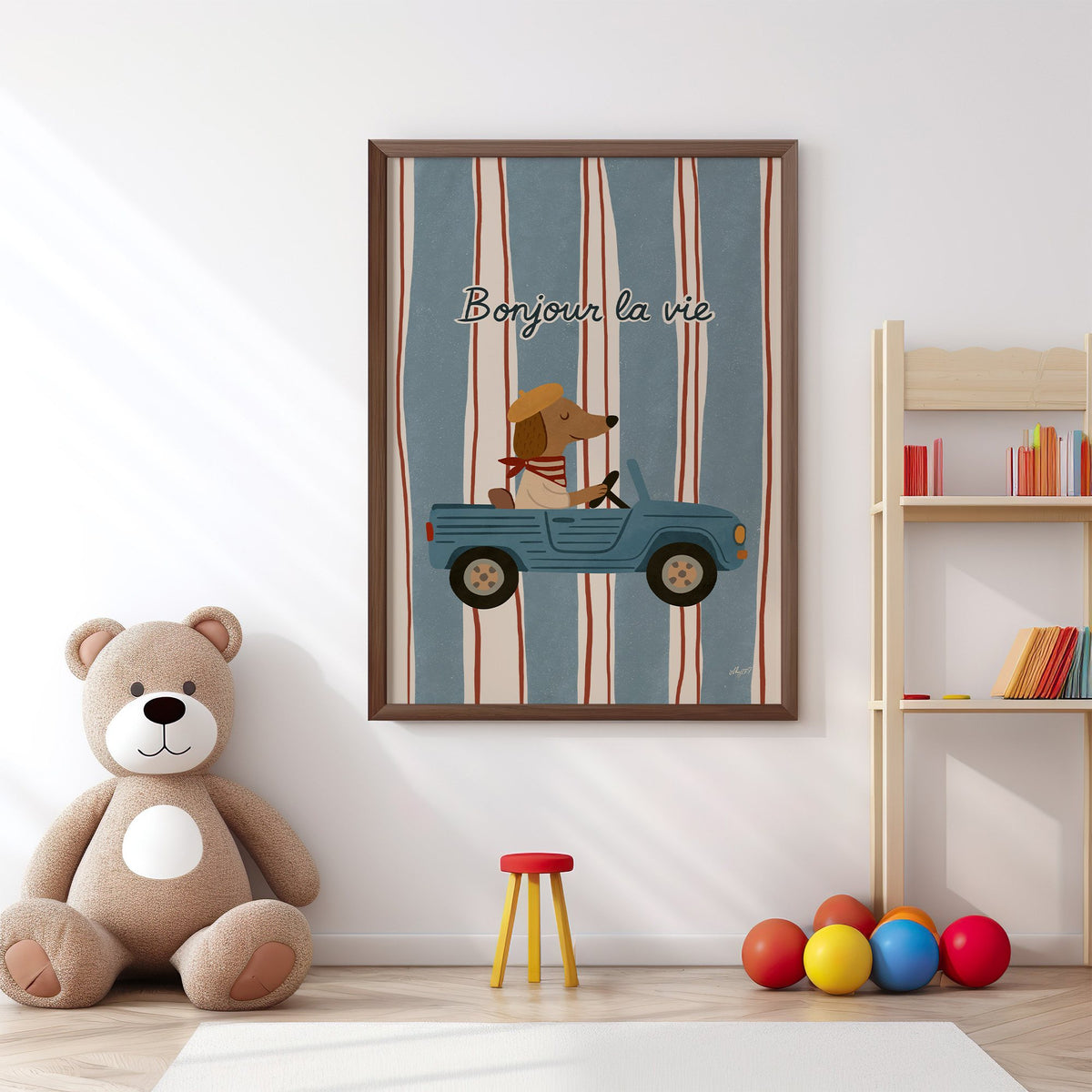 Dog driving car with french script nursery print in a walnut frame above a big teddy bear by a bookshelf