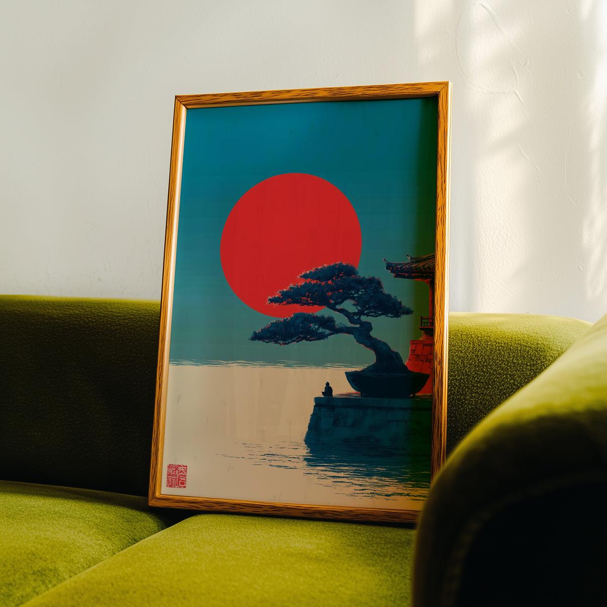 Bonsai pine under red sun print in an oak frame propped on a green velvet sofa