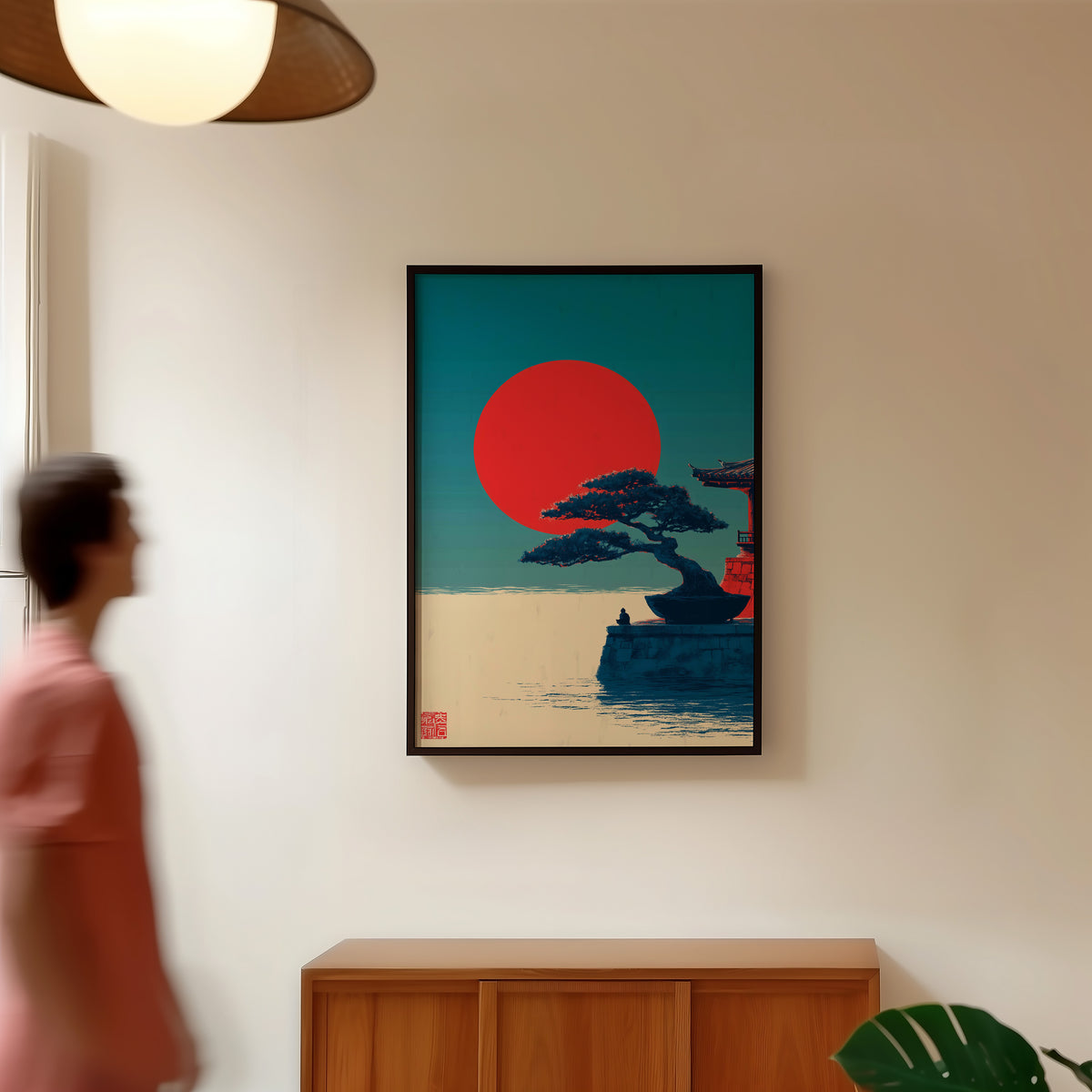 Bonsai pine under red sun print in a black frame in a hallway under a rattan pendant