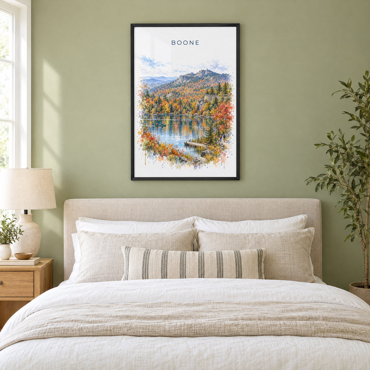 Boone, North Carolina watercolor print in a black frame above an upholstered headboard in a sage green bedroom