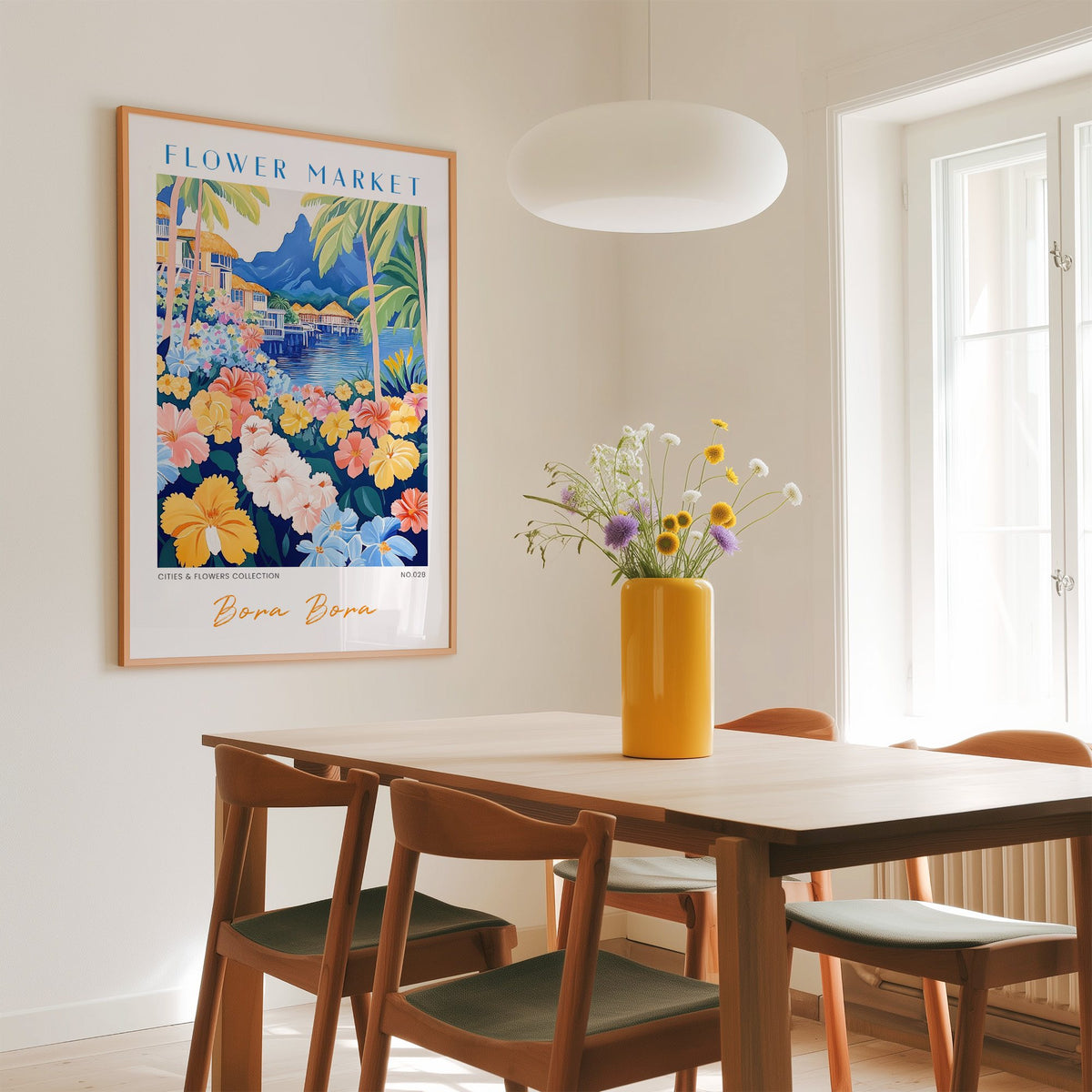 Bora Bora flower market print in an oak frame above a dining table with a yellow vase and white pendant light
