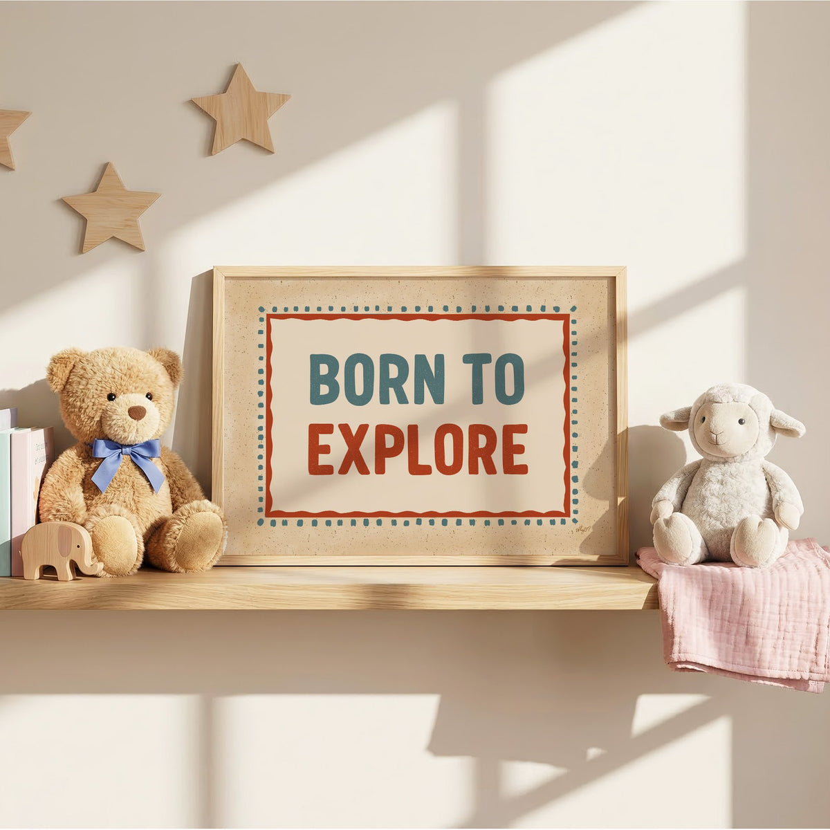 Born to explore retro quote nursery print in an oak frame on a wall shelf between a teddy bear and a toy lamb