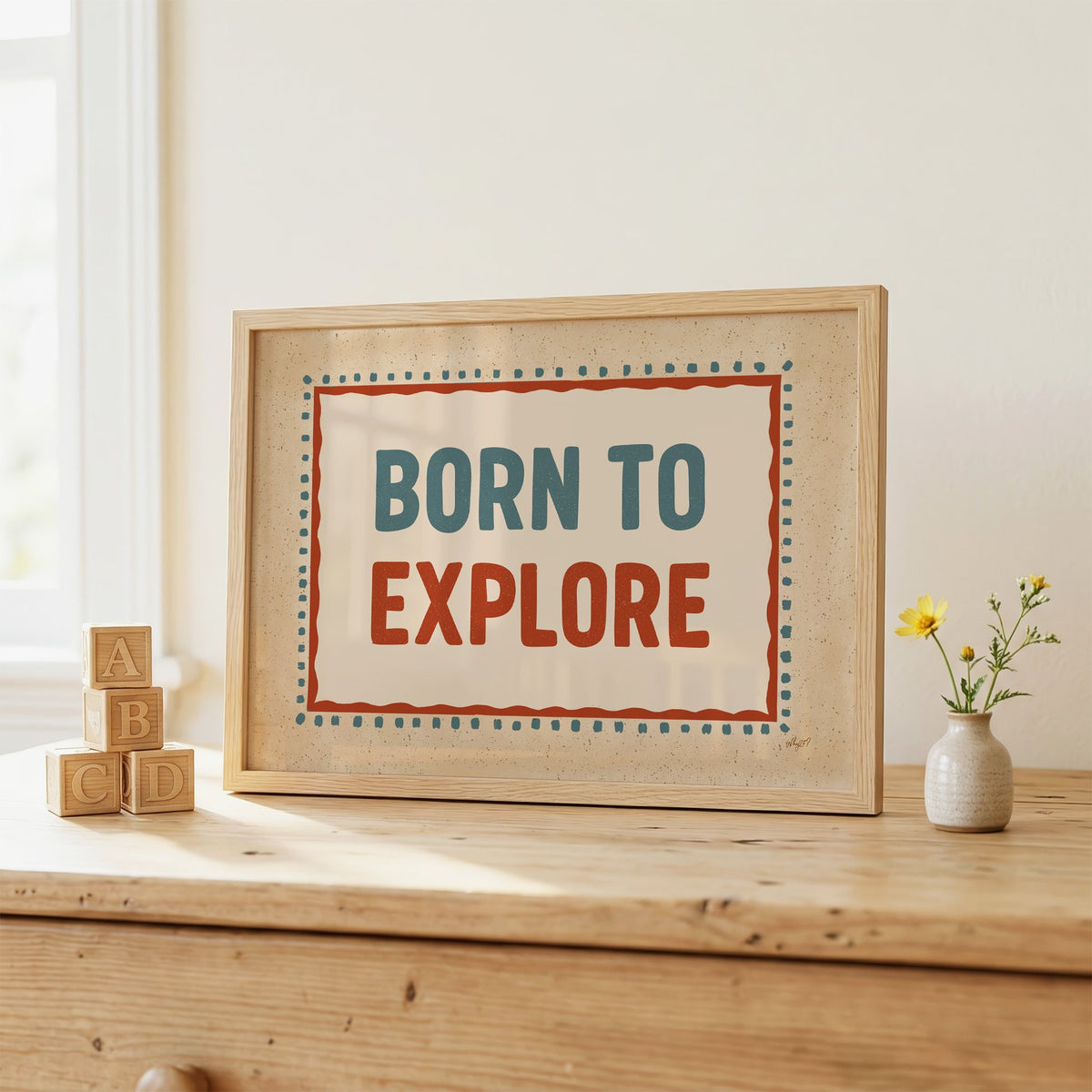Born to explore retro quote nursery print in an oak frame on a wooden dresser beside ABC blocks