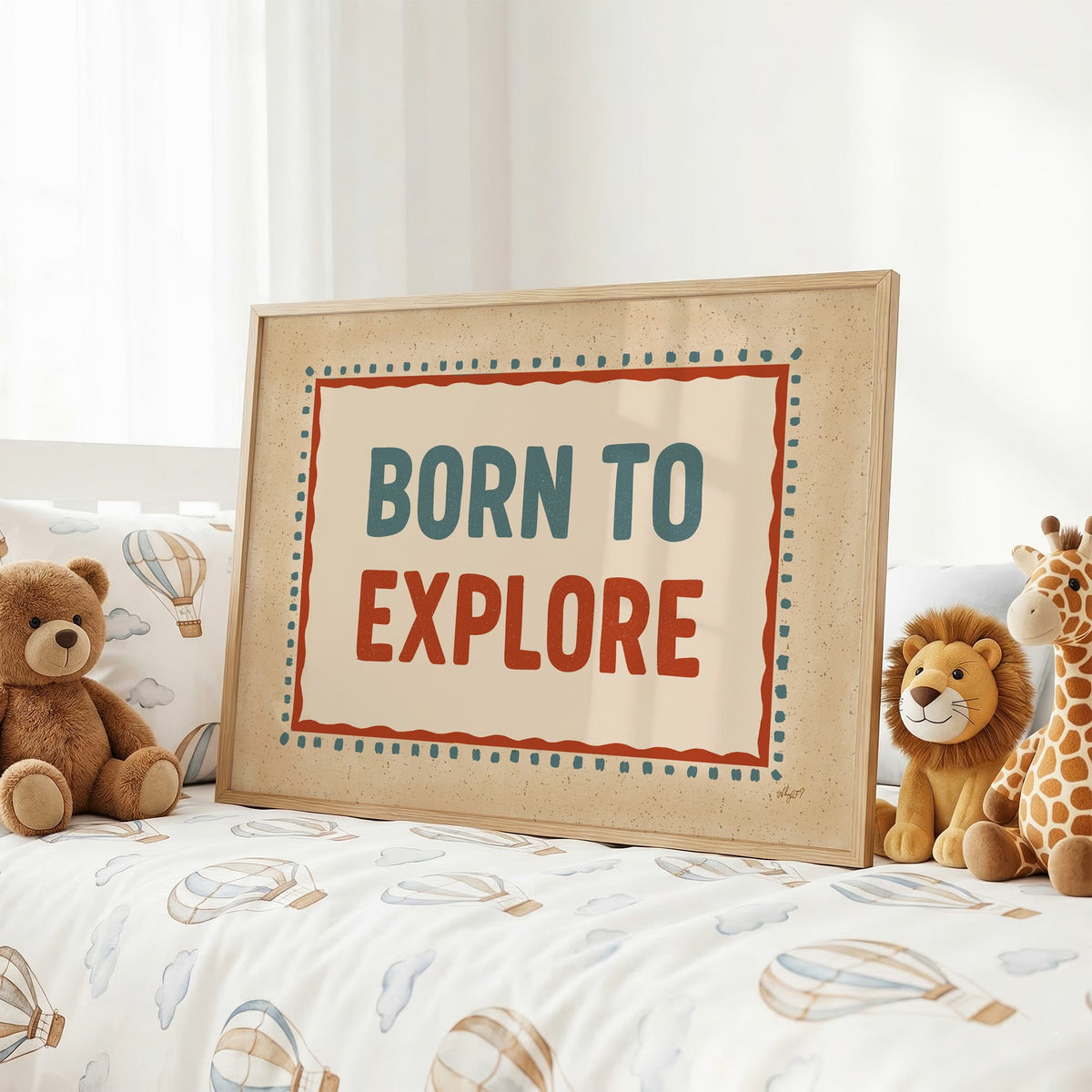 Born to explore retro quote nursery print in an oak frame on a kids bed with hot air balloon bedding