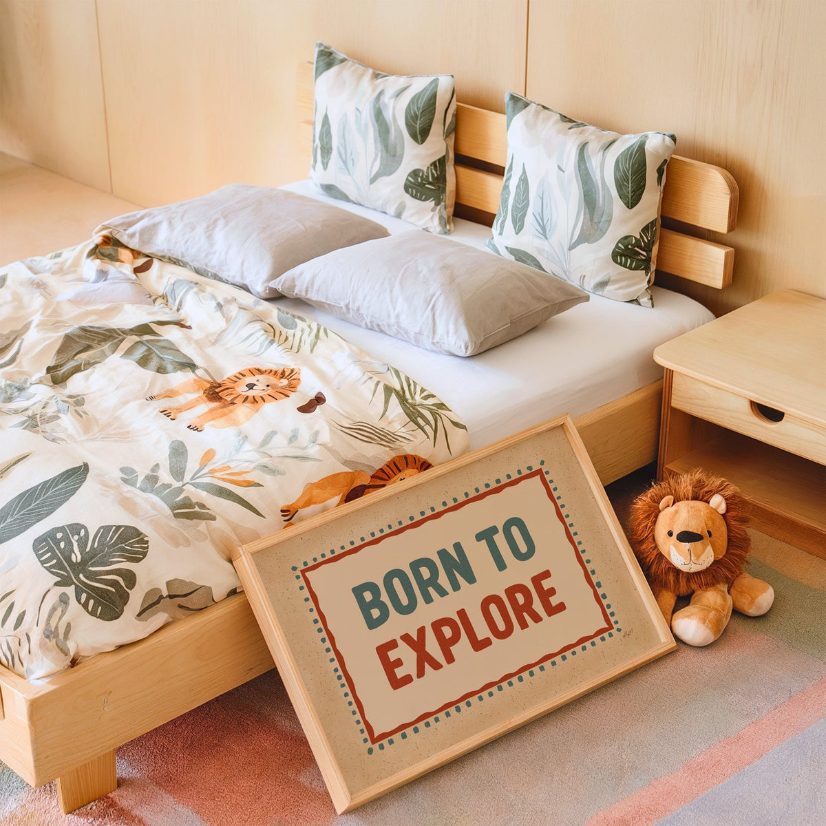 Born to explore retro quote nursery print in an oak frame leaning on a kids bed by a lion plush