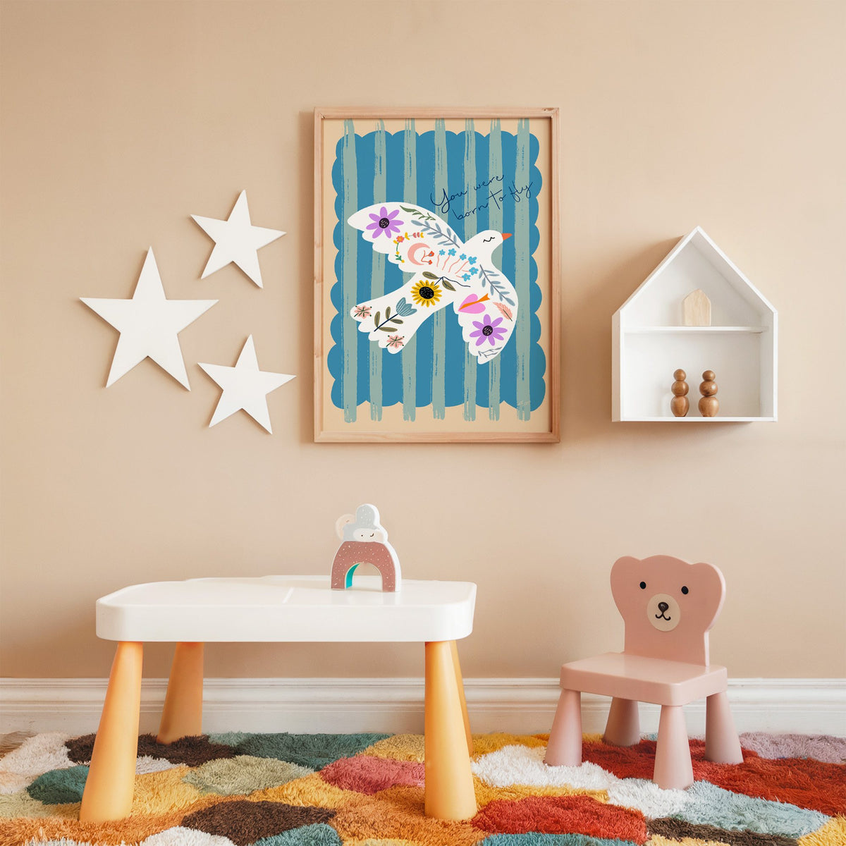 White dove covered in flowers nursery print in an oak frame on a peach wall above a kids table with wall stars