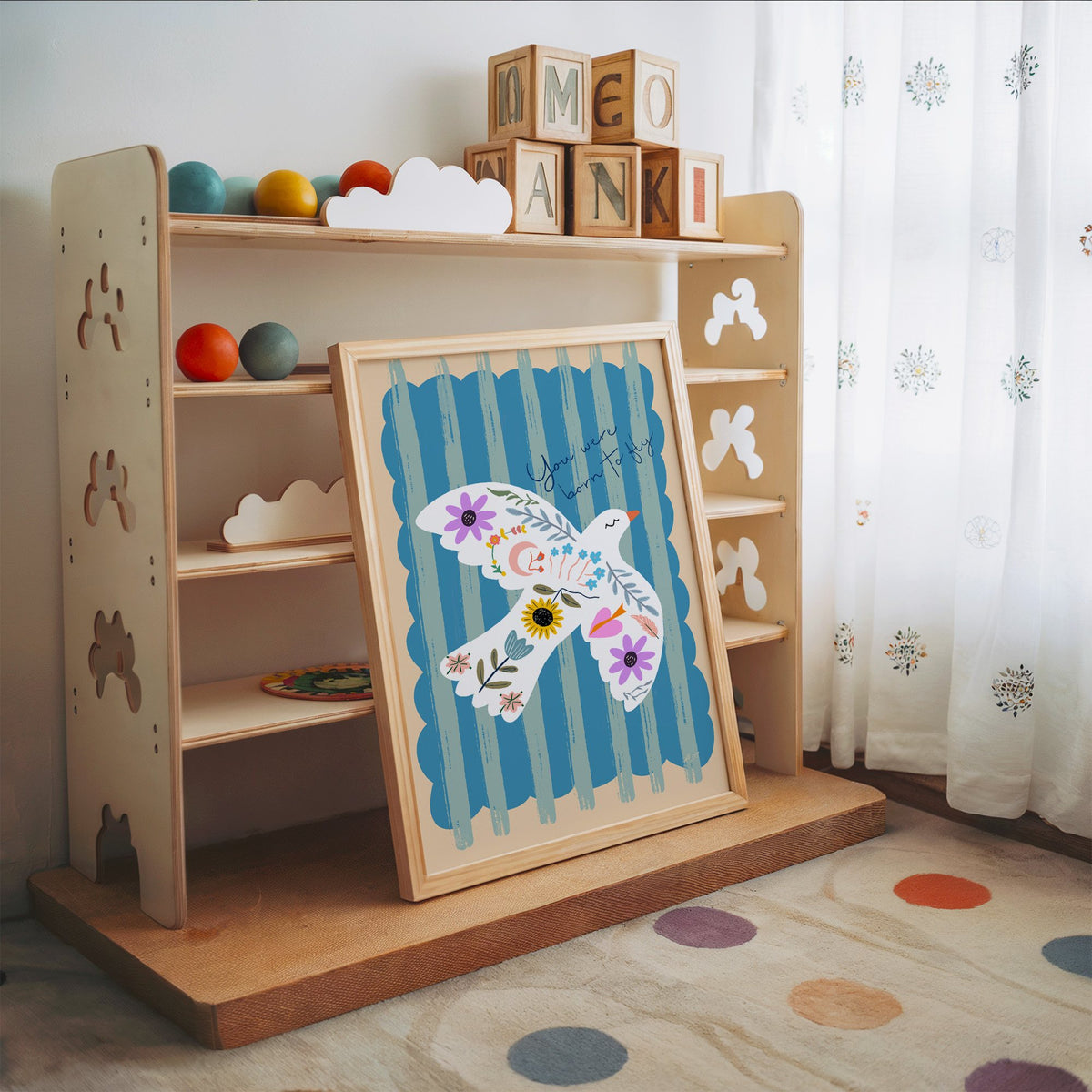 White dove covered in flowers nursery print in an oak frame leaning on a toy shelf with wooden letter blocks