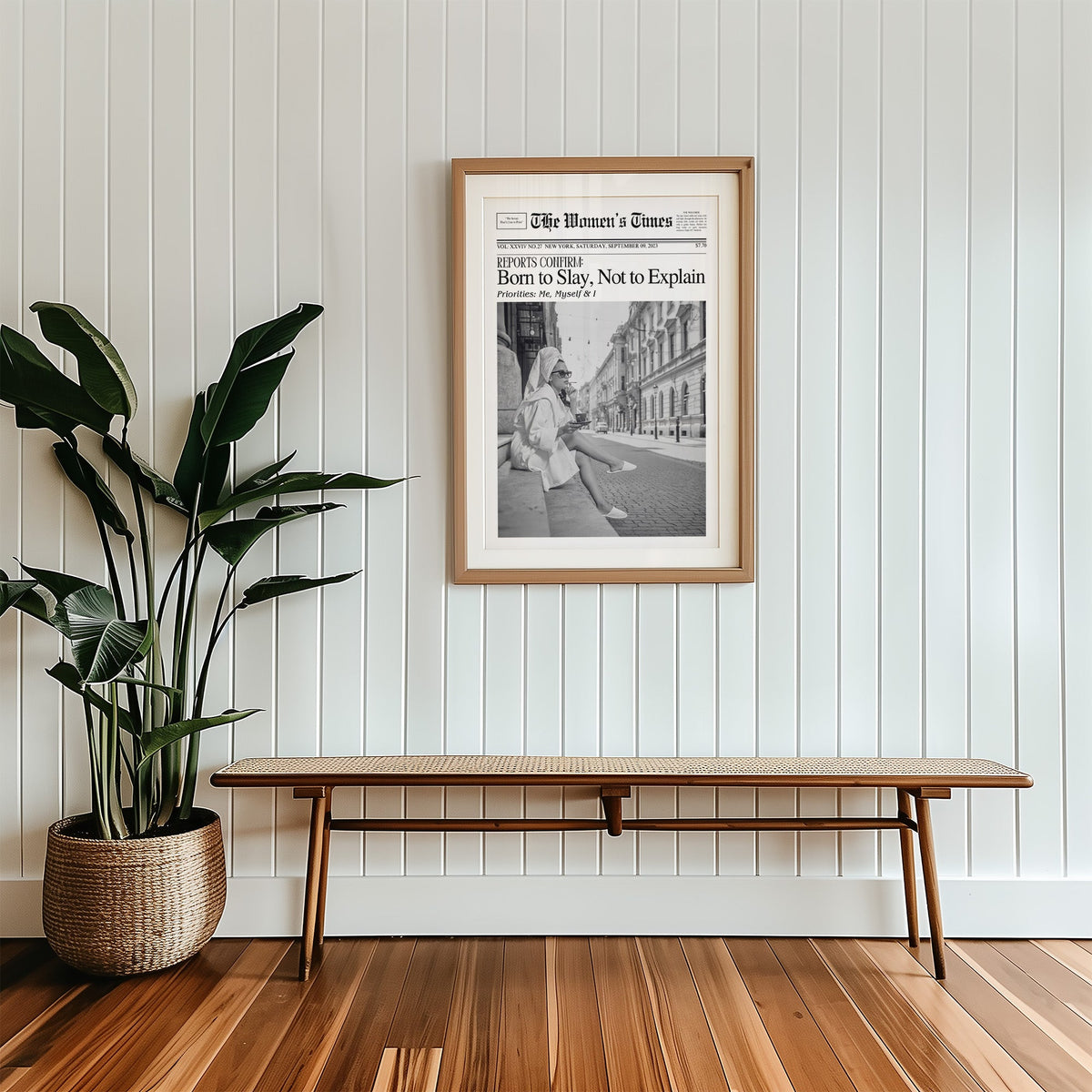 Mock front page with woman in robe on a cobbled street print in a wood frame with a white mat above a cane bench