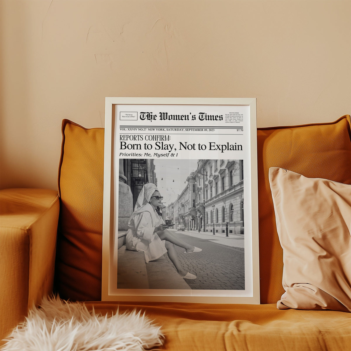 Mock front page with woman in robe on a cobbled street print in a white frame leaning on a mustard velvet sofa