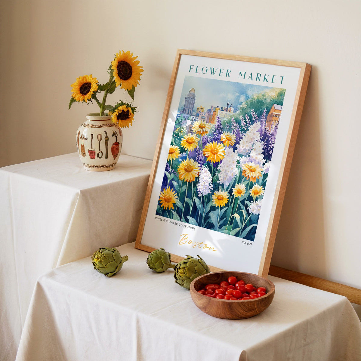 Boston flower market print in an oak frame leaning on a linen-draped table beside a vase of sunflowers