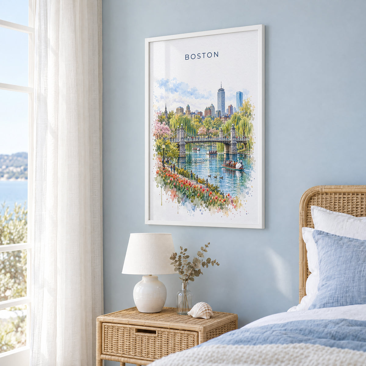 Boston Public Garden watercolor print in a white frame on a pale blue wall beside a rattan bed in a coastal bedroom