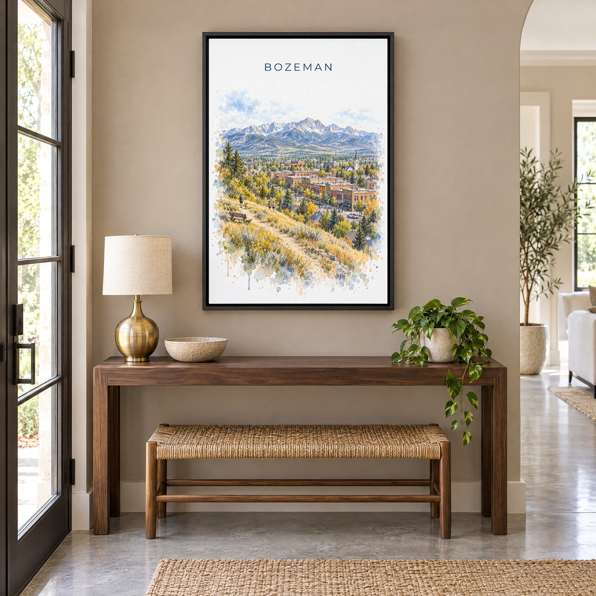 Bozeman watercolor print as a black floater canvas above a walnut console and woven bench in an entryway