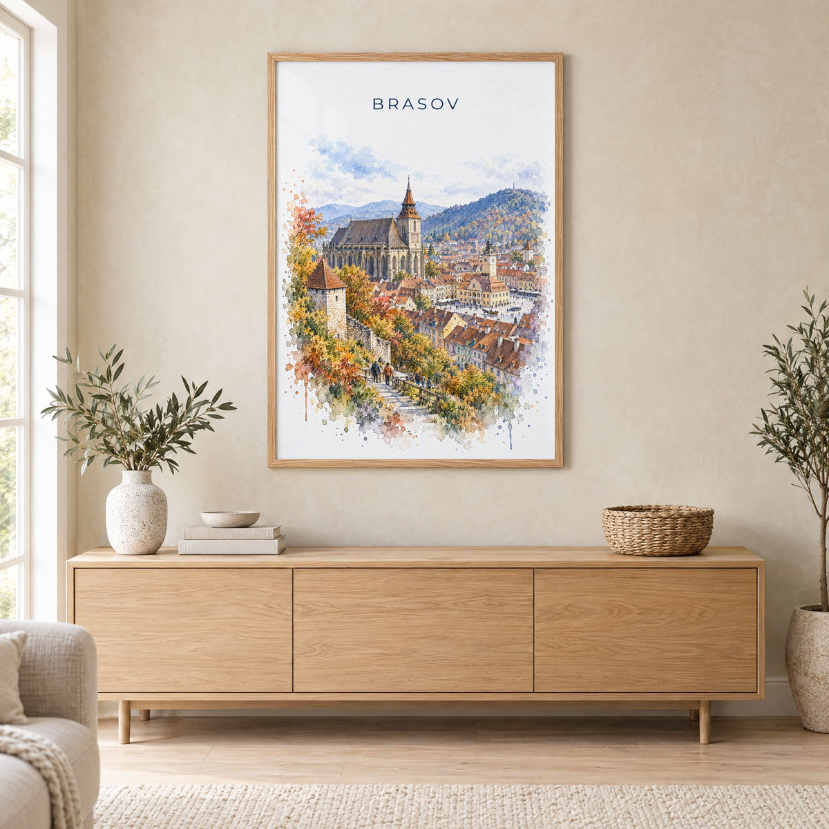 Brasov watercolor print in an oak frame above a light wood sideboard in a Scandinavian living room