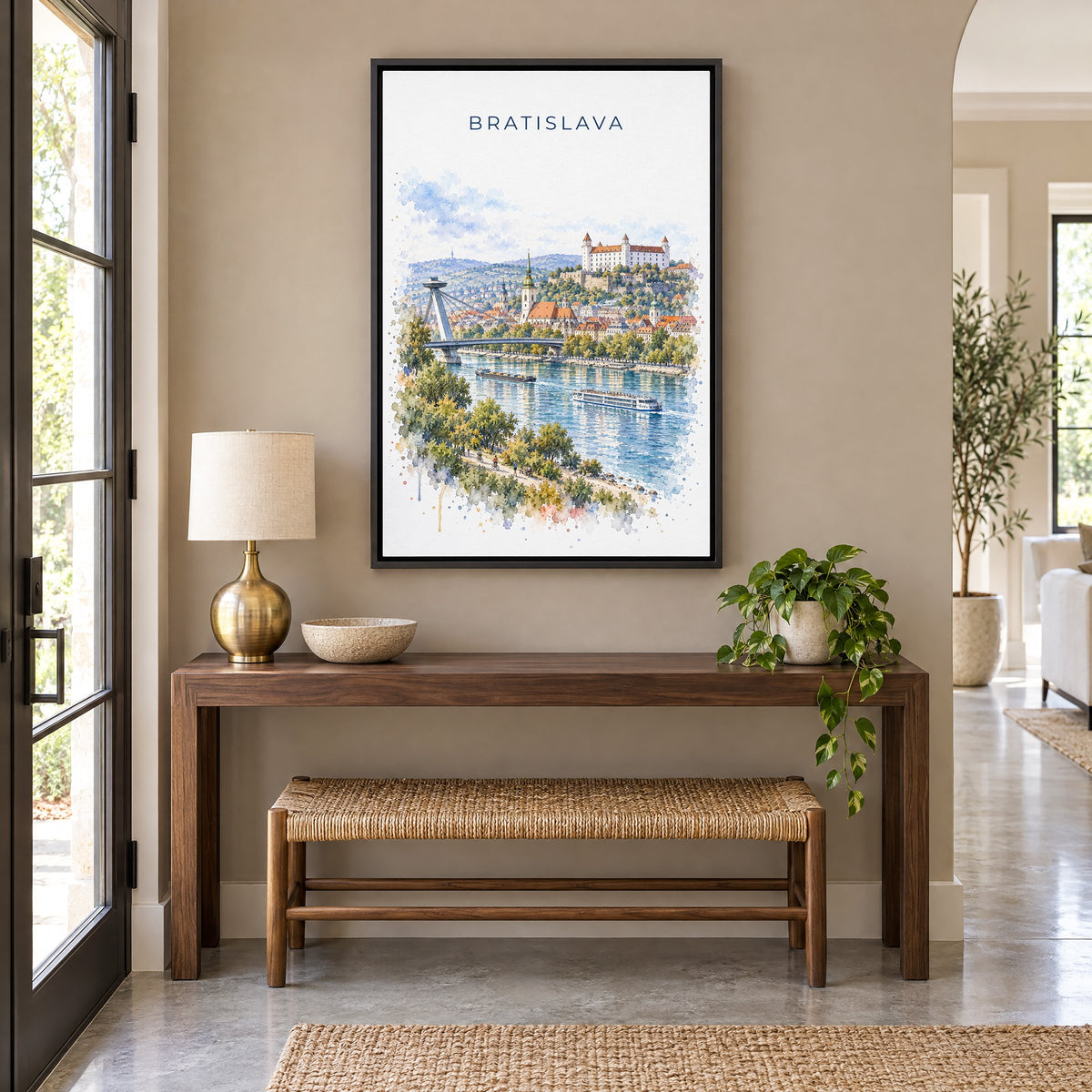 Bratislava watercolor print as a black floater canvas above a walnut console and woven bench in an entryway