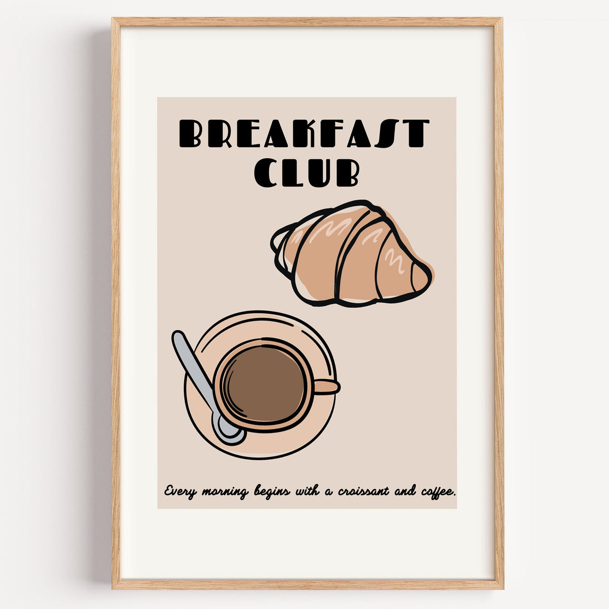 Breakfast Club croissant and coffee print in a light oak frame on a plain white wall